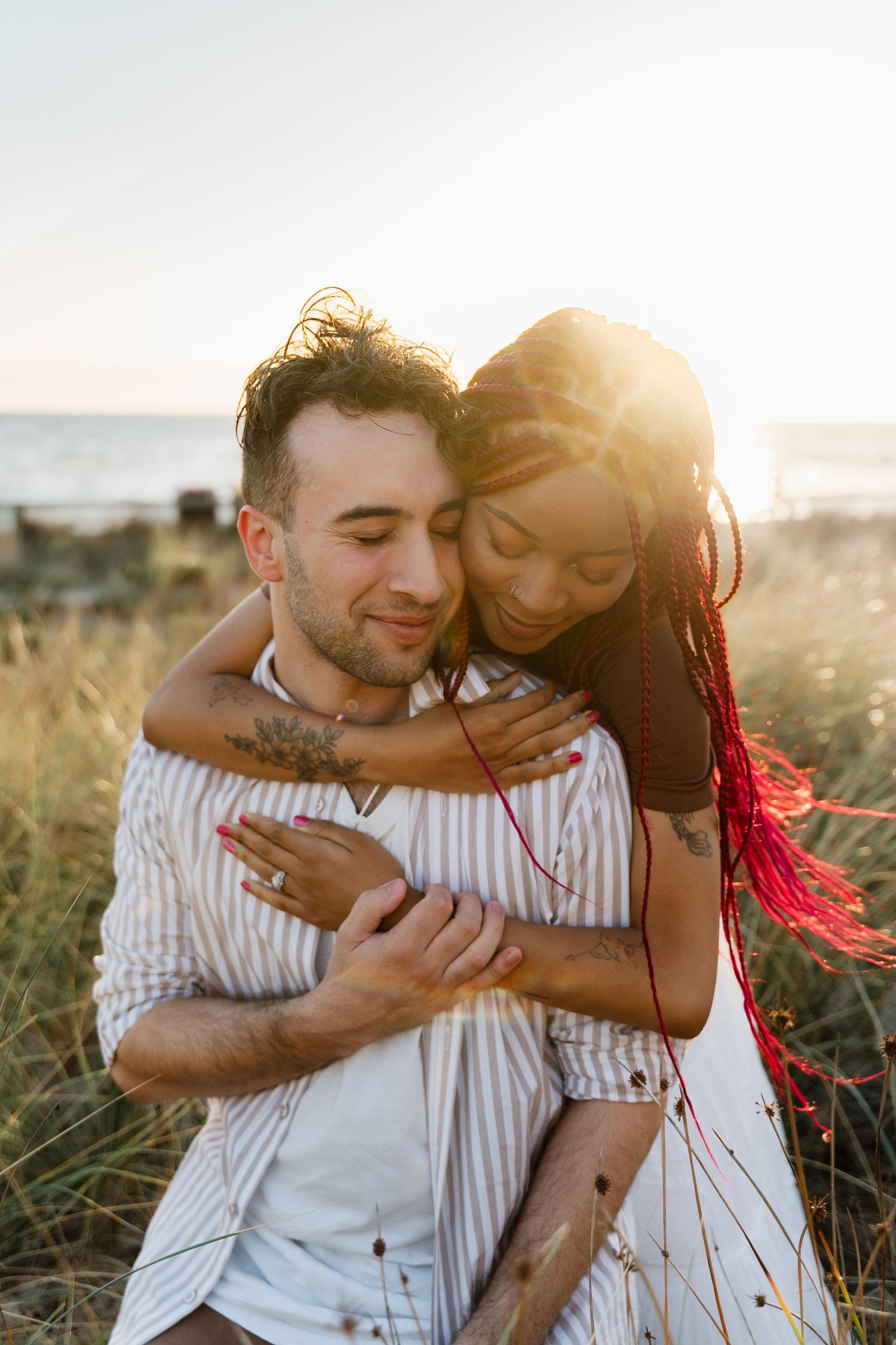 Intimate couple portrait at beach during golden hour showing genuine joy and connection.