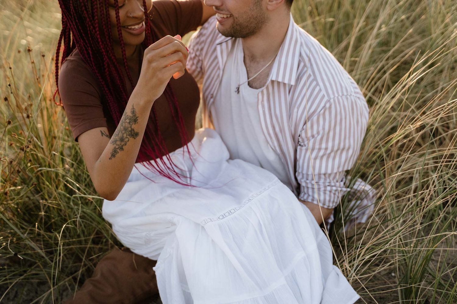 Couple sharing intimate moment in tall grass field.