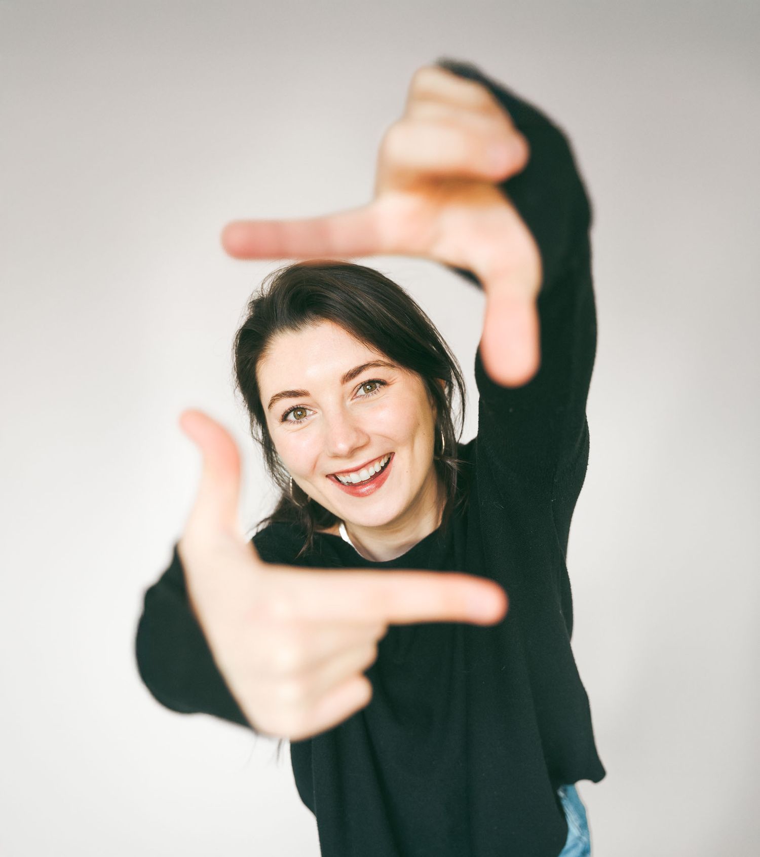 Person in black sweater making a creative frame gesture with hands.