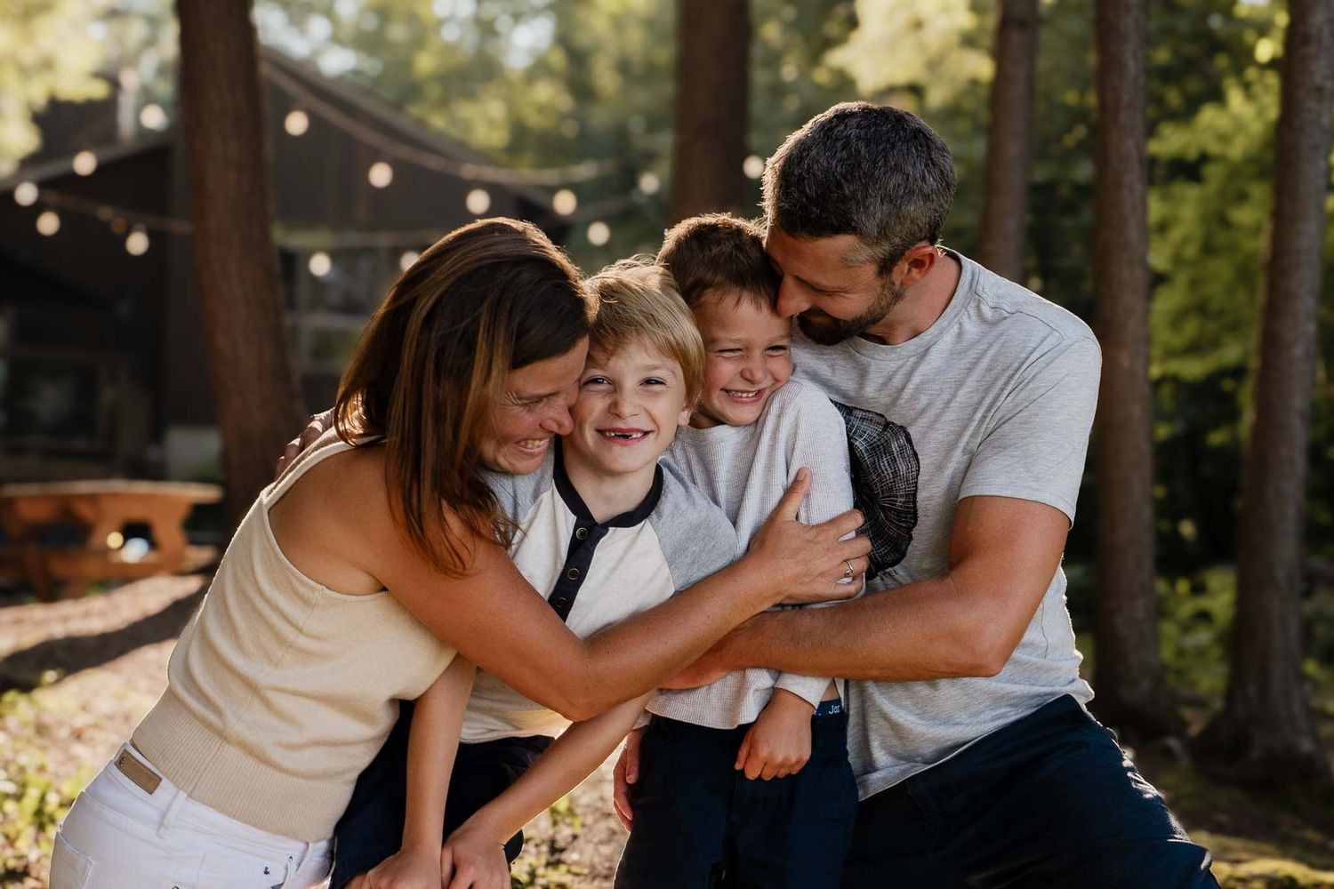 Family sharing a joyful moment together outdoors with string lights in the background.