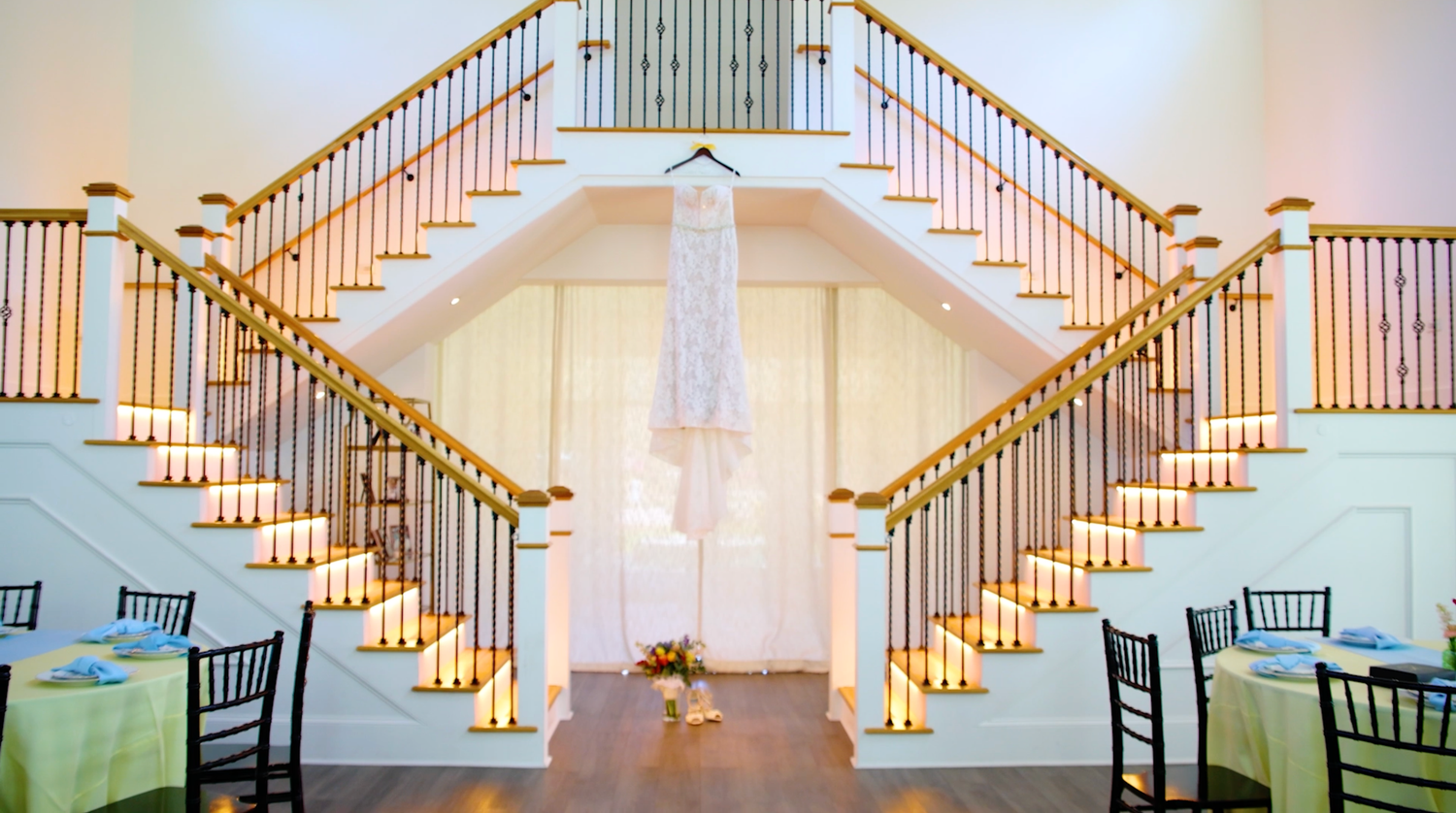 Elegant banquet hall interior with white walls and wooden staircases decorated with warm ambient lighting for events.