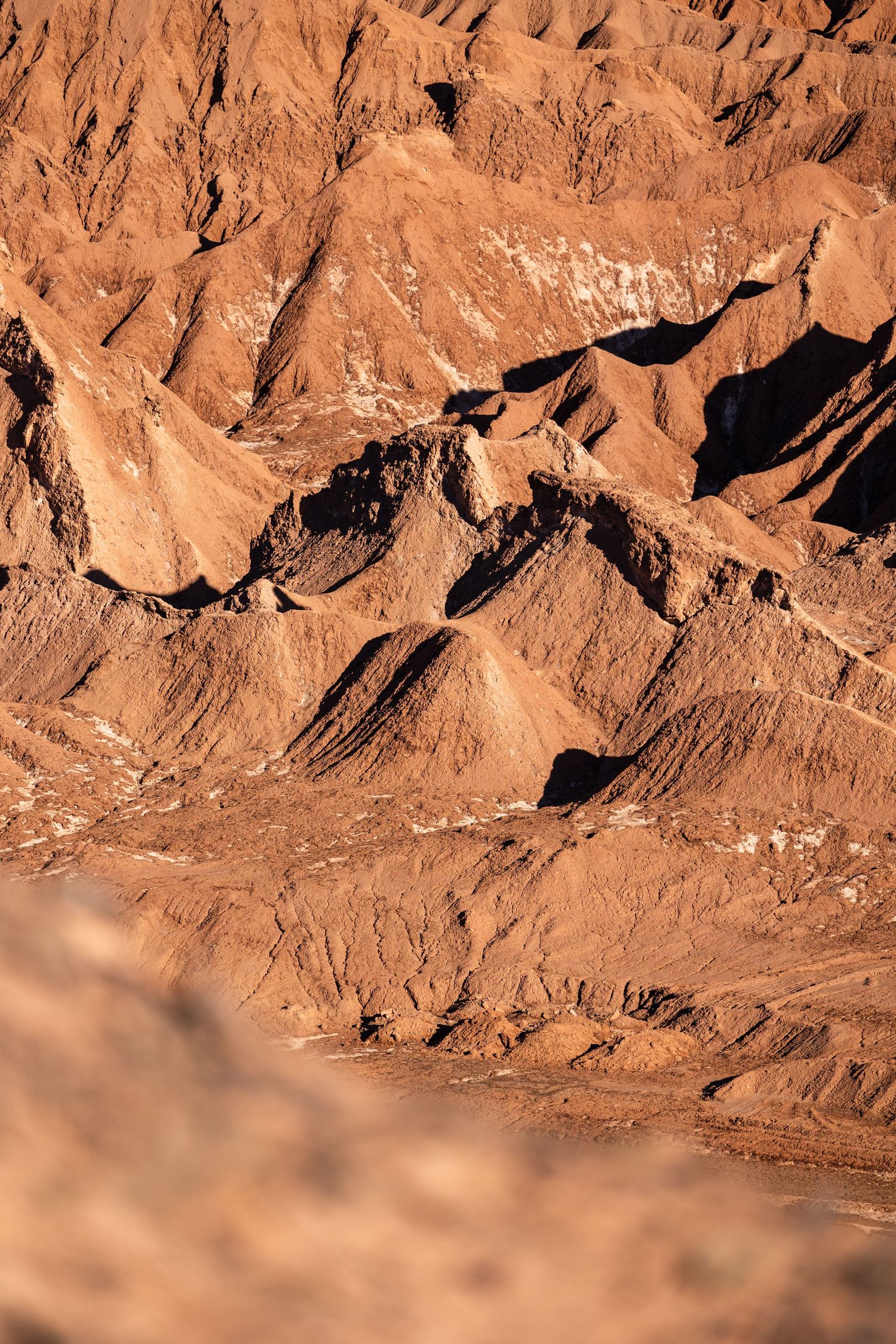 Rugged reddish-brown rock formations in a desert landscape show dramatic geological layers and steep cliffs.