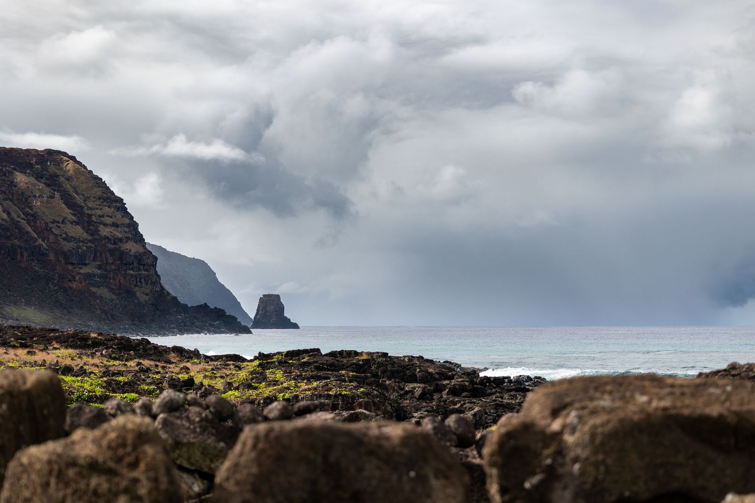 Dramatic coastal landscape with rugged cliffs and rocky shore under moody clouds at oceanside.