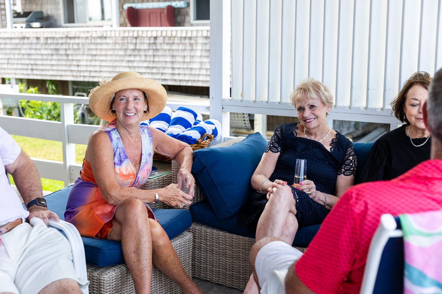 A group of people sitting on outdoor patio furniture during a casual summer gathering.
