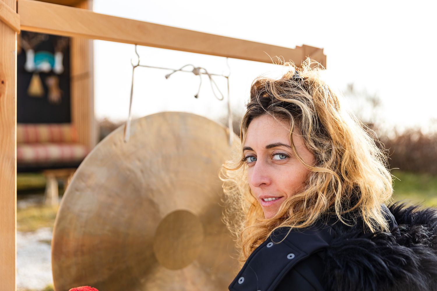 Portrait by a gong instrument at golden hour with warm sunlight.