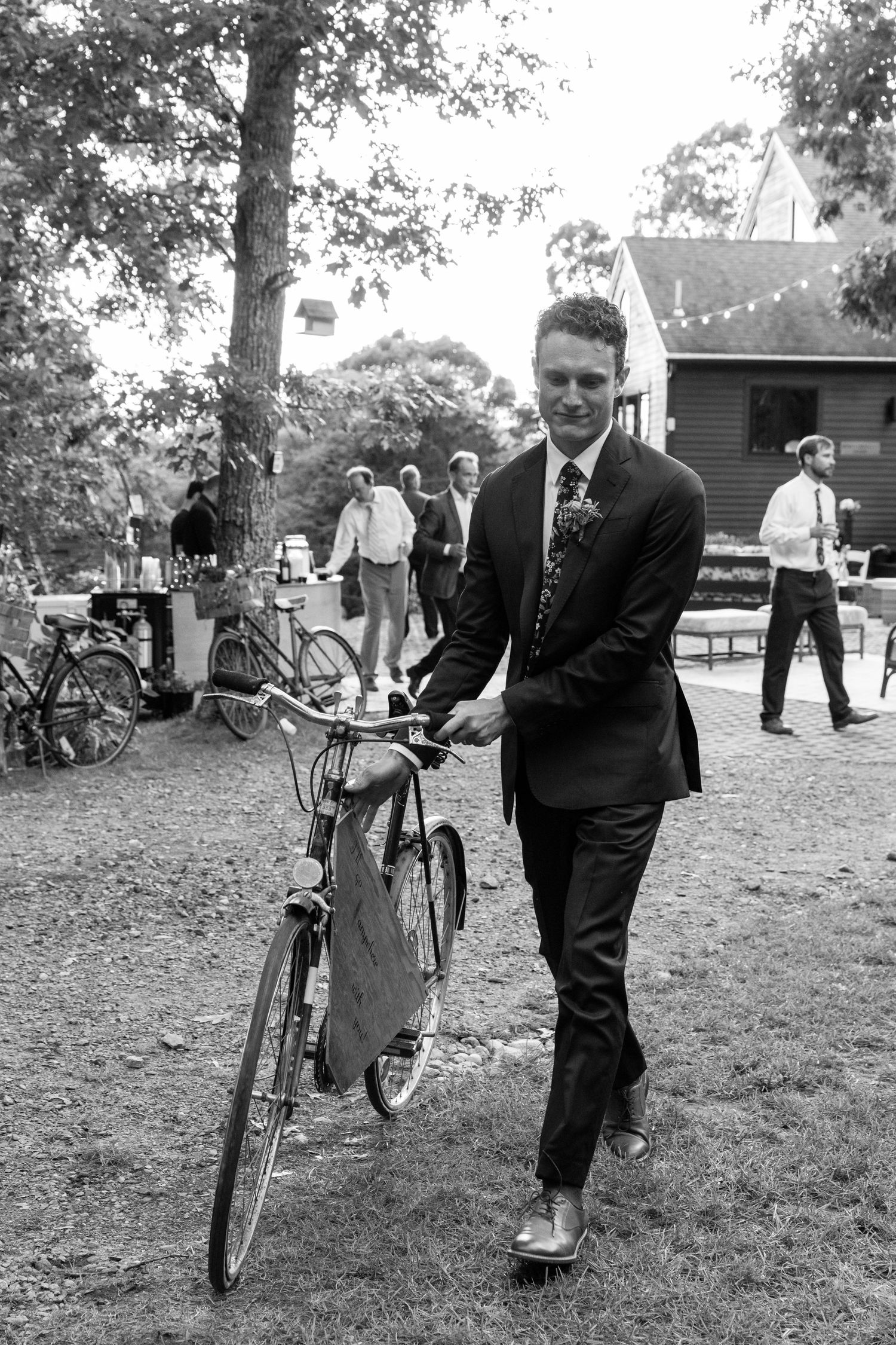 Vintage black and white photos show a person helping children balance on bicycles during an outdoor community gathering.