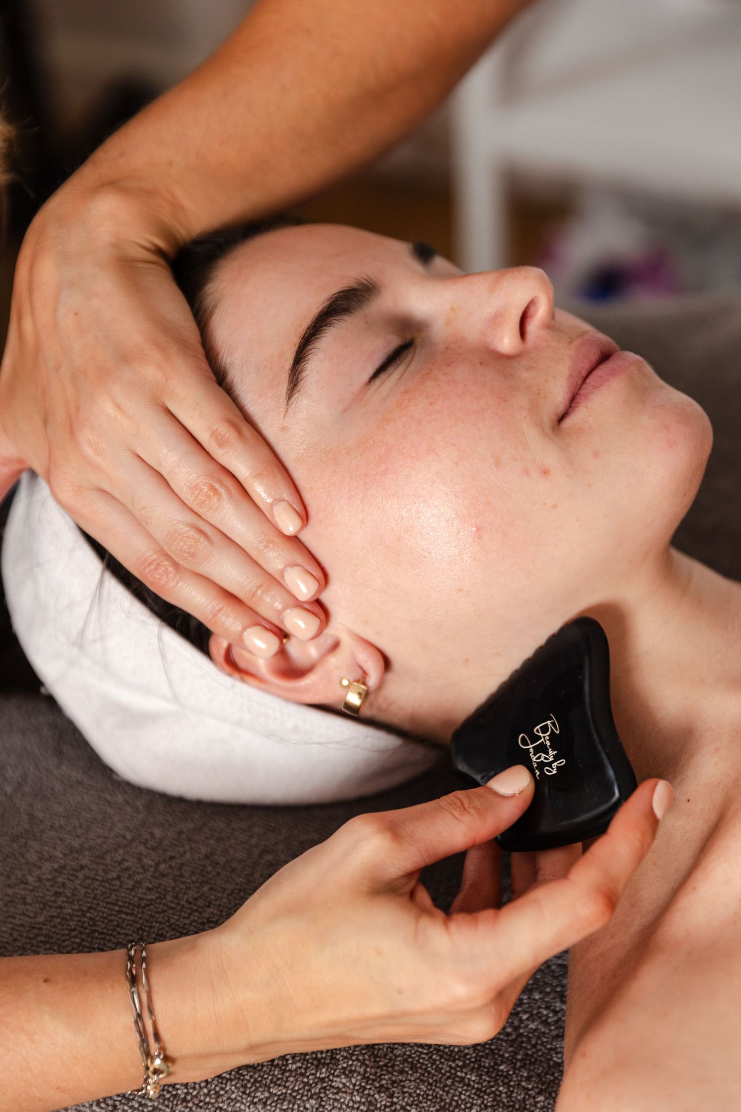 Close up of facial massage treatment using gua sha tool at luxury spa.