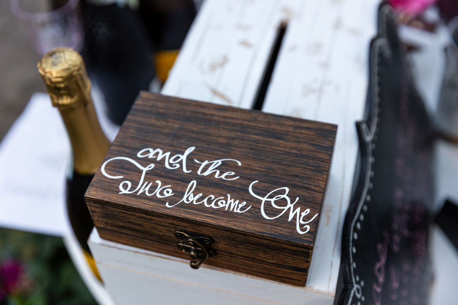Wooden welcome signs with white calligraphy writing displayed at a rustic wedding reception.