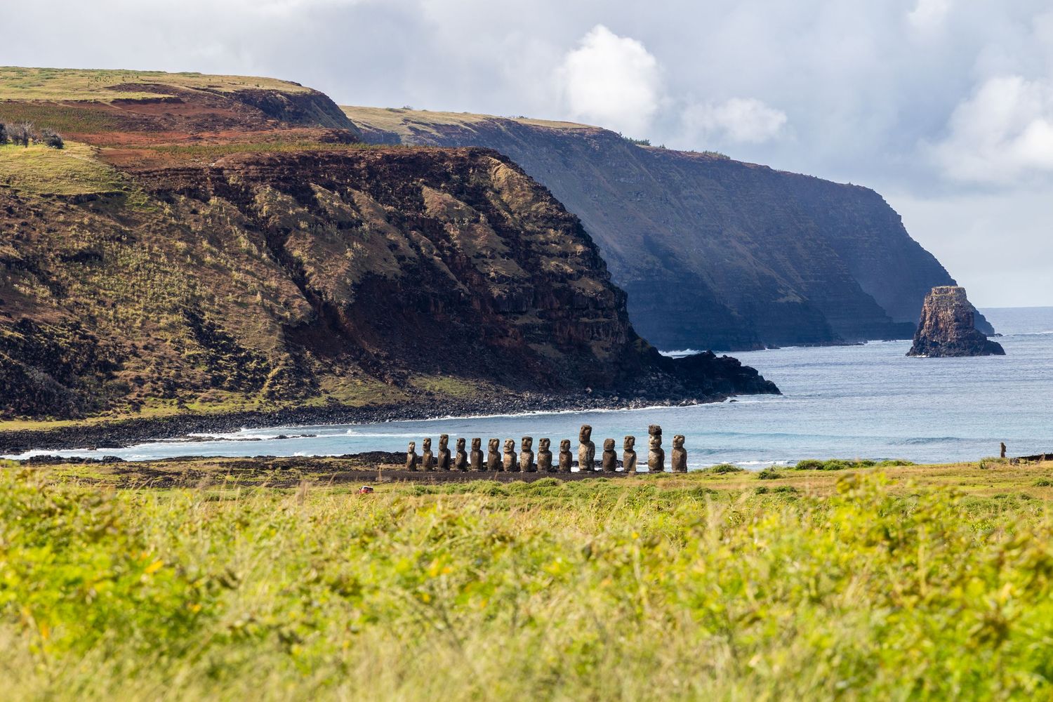 Panoramic view of Easter Island's rugged coastline showcasing iconic Moai stone statues against dramatic cliffs and ocean.