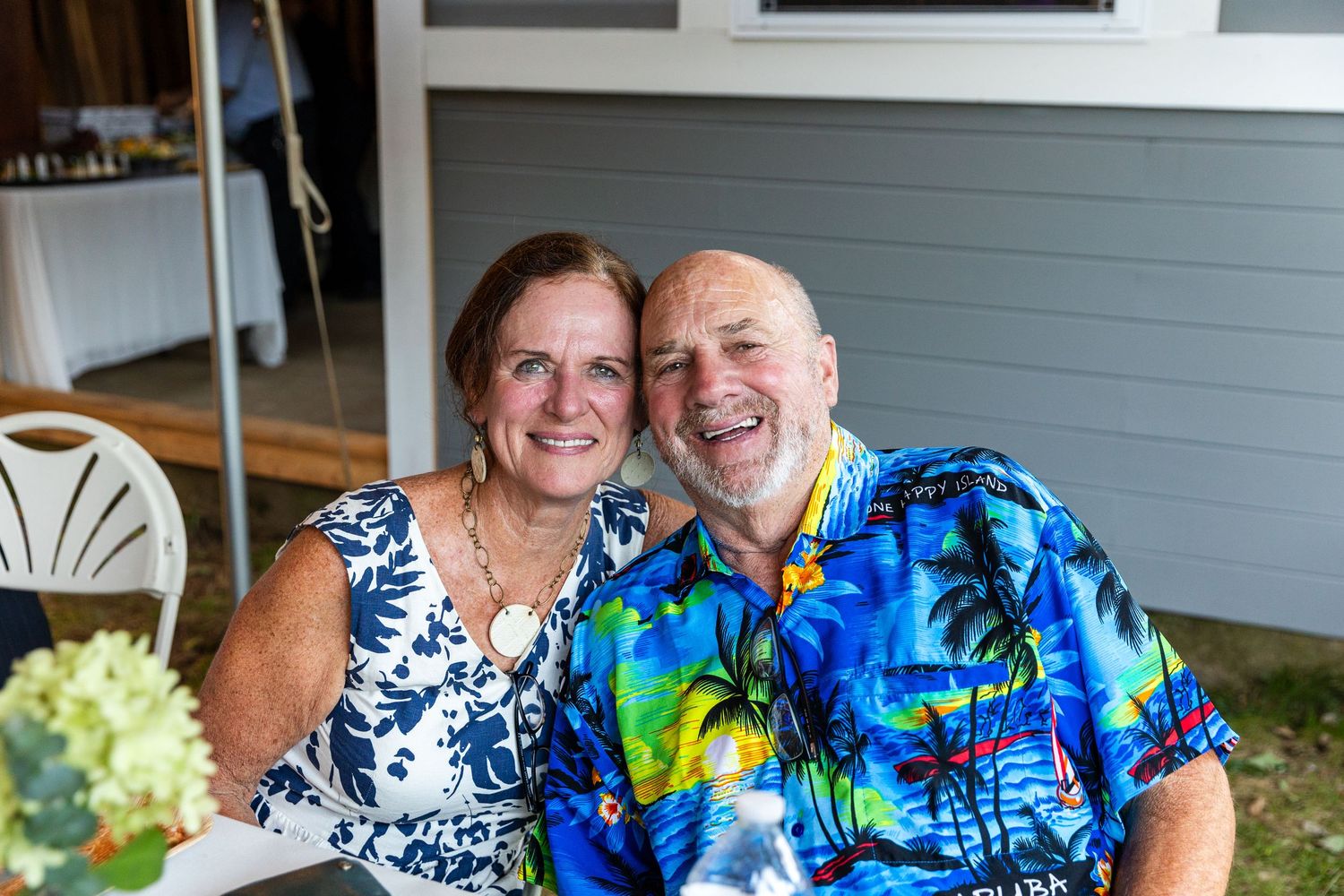 A couple wearing matching Hawaiian prints share a happy moment together on an outdoor patio.