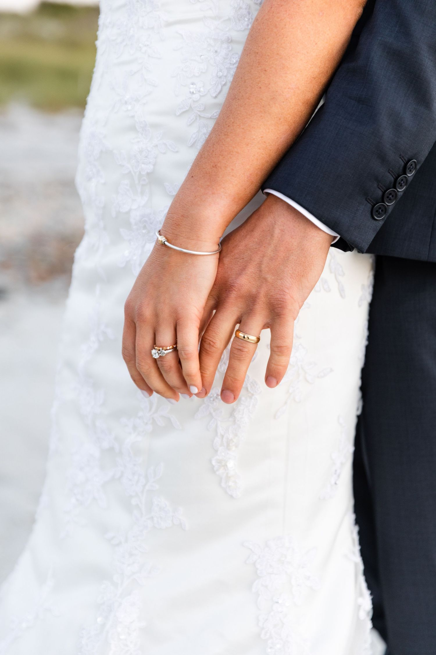 Close-up series showing engagement ring and wedding band details on a bride's hand against white lace dress fabric.