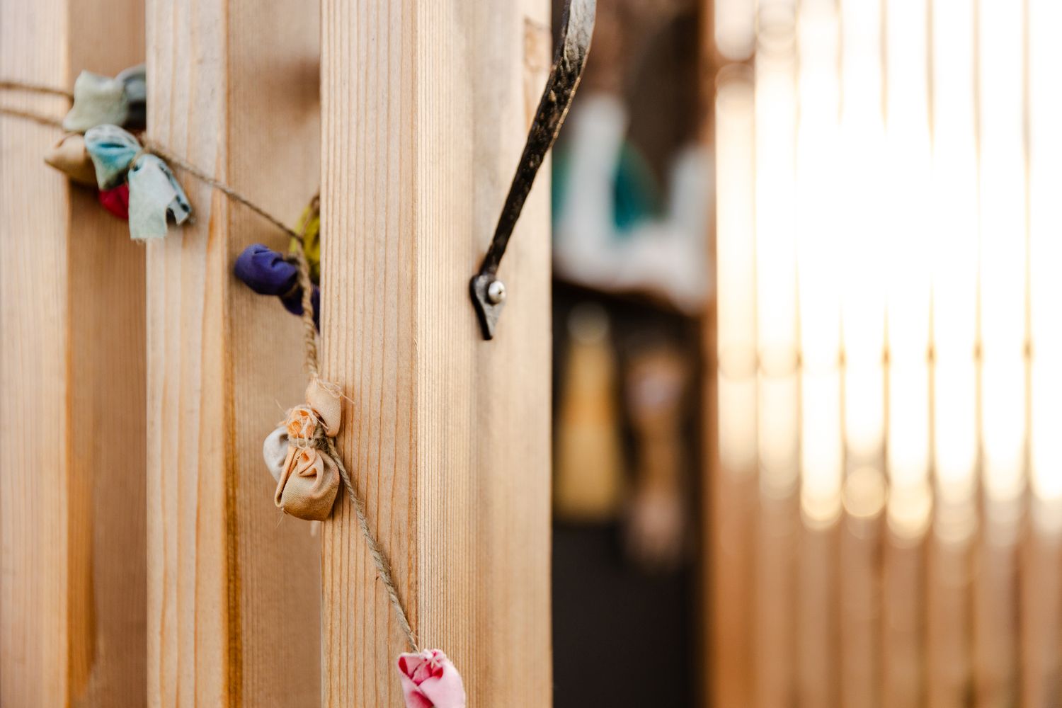 Small decorative trinkets and ornaments hanging on wooden slats in warm lighting.