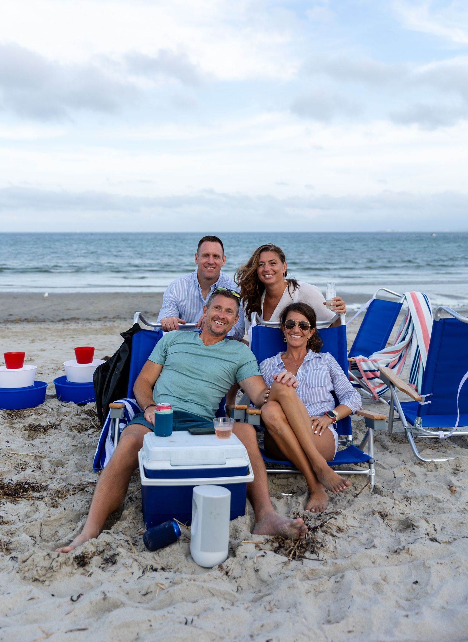 Friends enjoying a casual beach day with chairs and cooler along the ocean shore.
