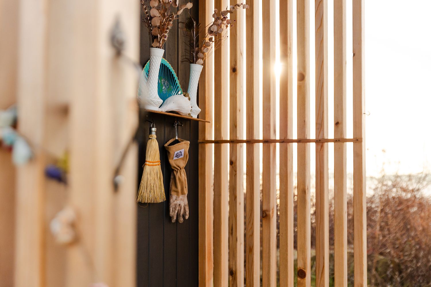 Decorative hanging wind chime with bunny ears against wooden slat wall in warm lighting.