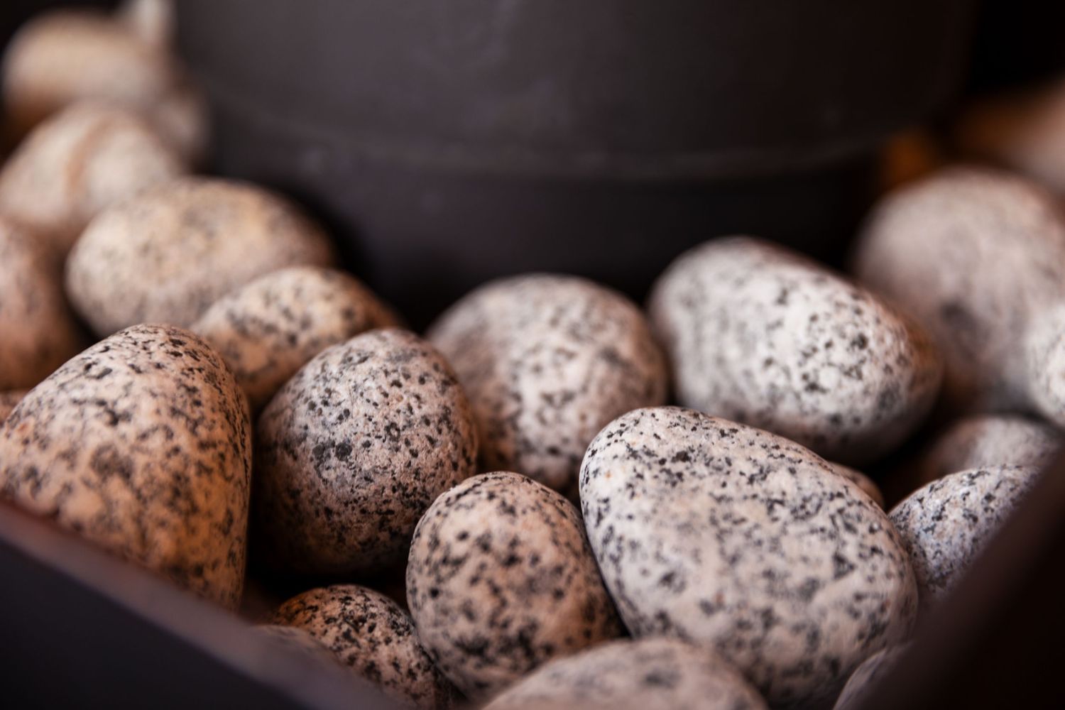 Close up view of speckled brown eggs with mottled shells arranged in a dark container.