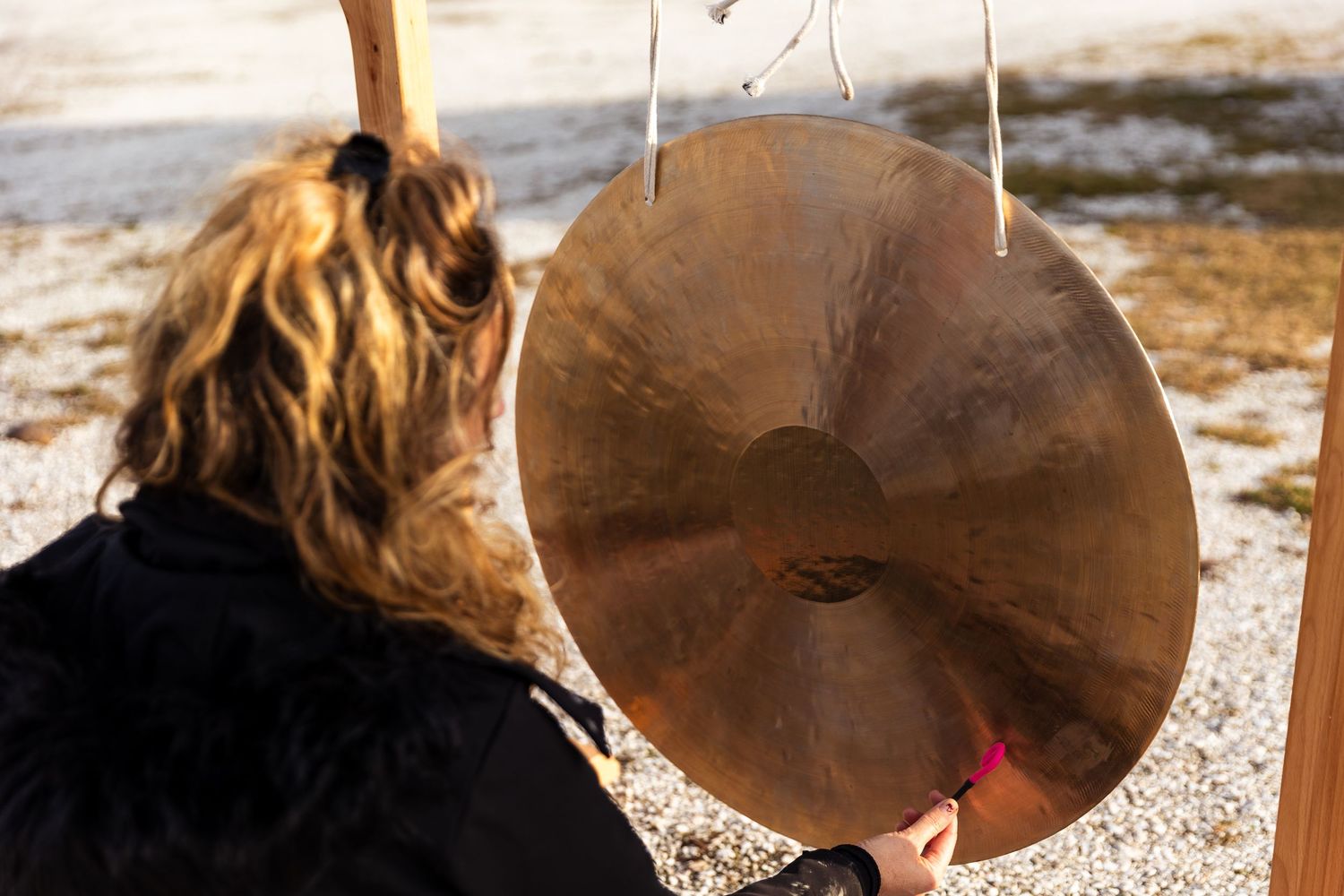 A series of images showing a person sitting outdoors playing a cymbal with a drumstick in varying sequential movements.