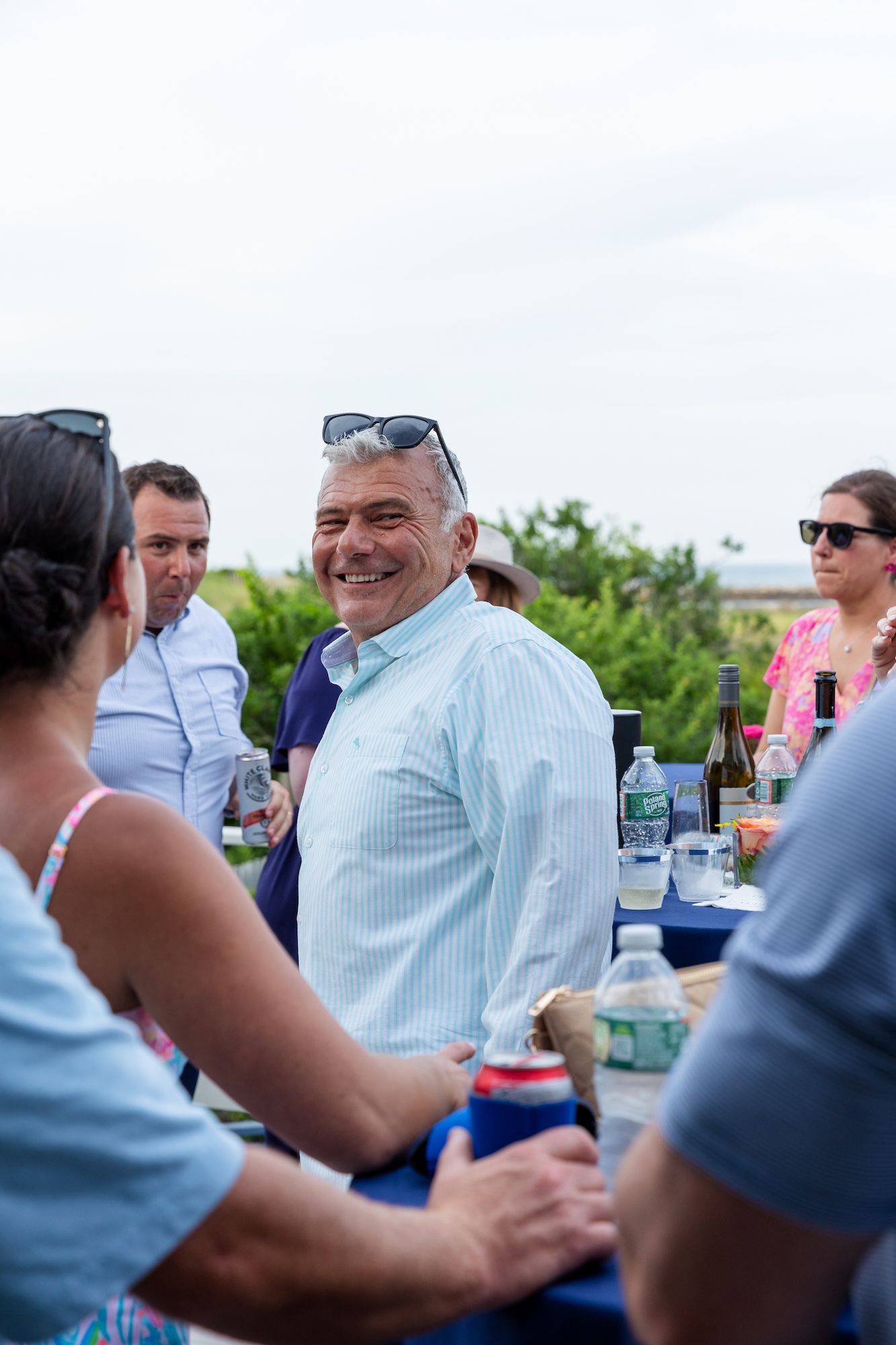 People enjoying drinks and conversation at an outdoor social gathering on a sunny day.