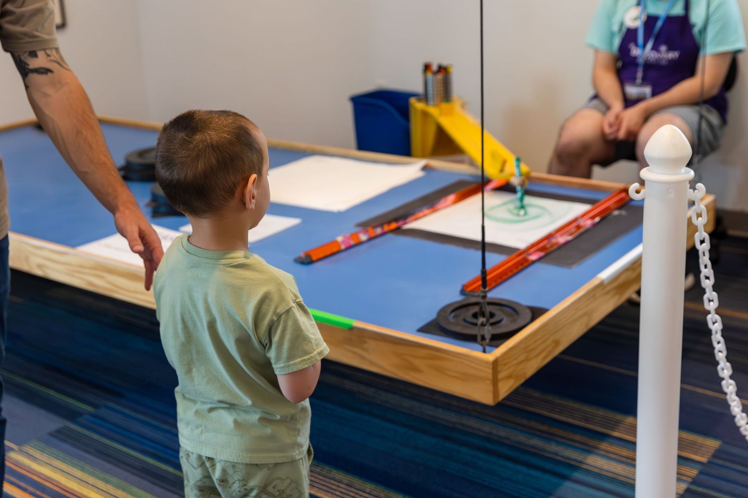 A child receives occupational therapy while playing hockey on a tabletop game board in a medical setting.