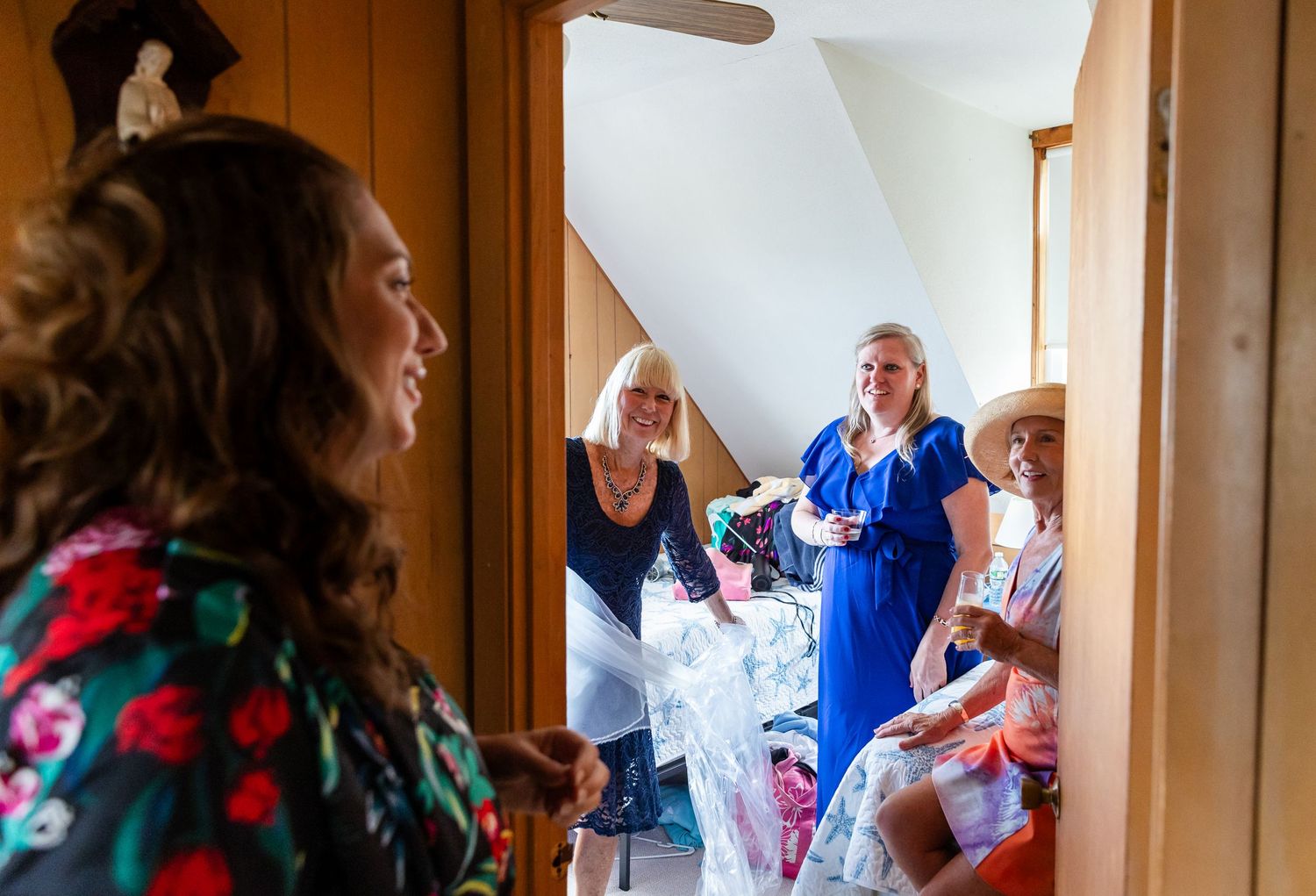 People gather in a bright hallway with white walls and wooden trim during a celebratory event.