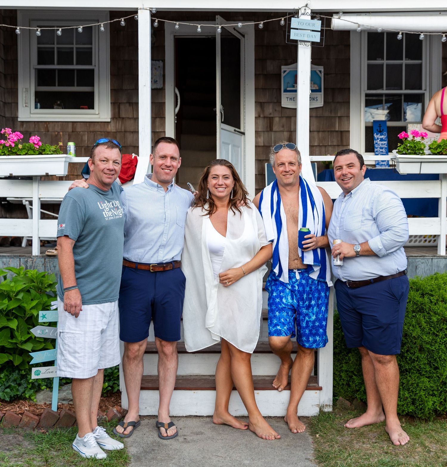 Casual group poses on porch at summer gathering in blue and white outfits with matching decor.