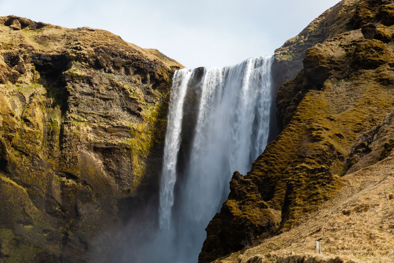 Majestic waterfall cascading down rocky cliff face in dramatic natural landscape.