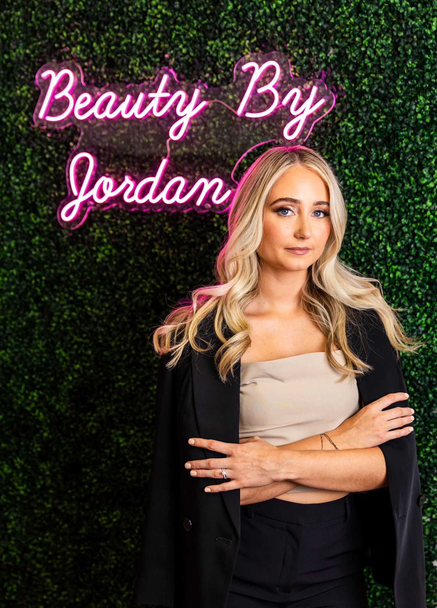 Professional headshots on green hedge backdrop showing confident poses and neon pink studio sign.