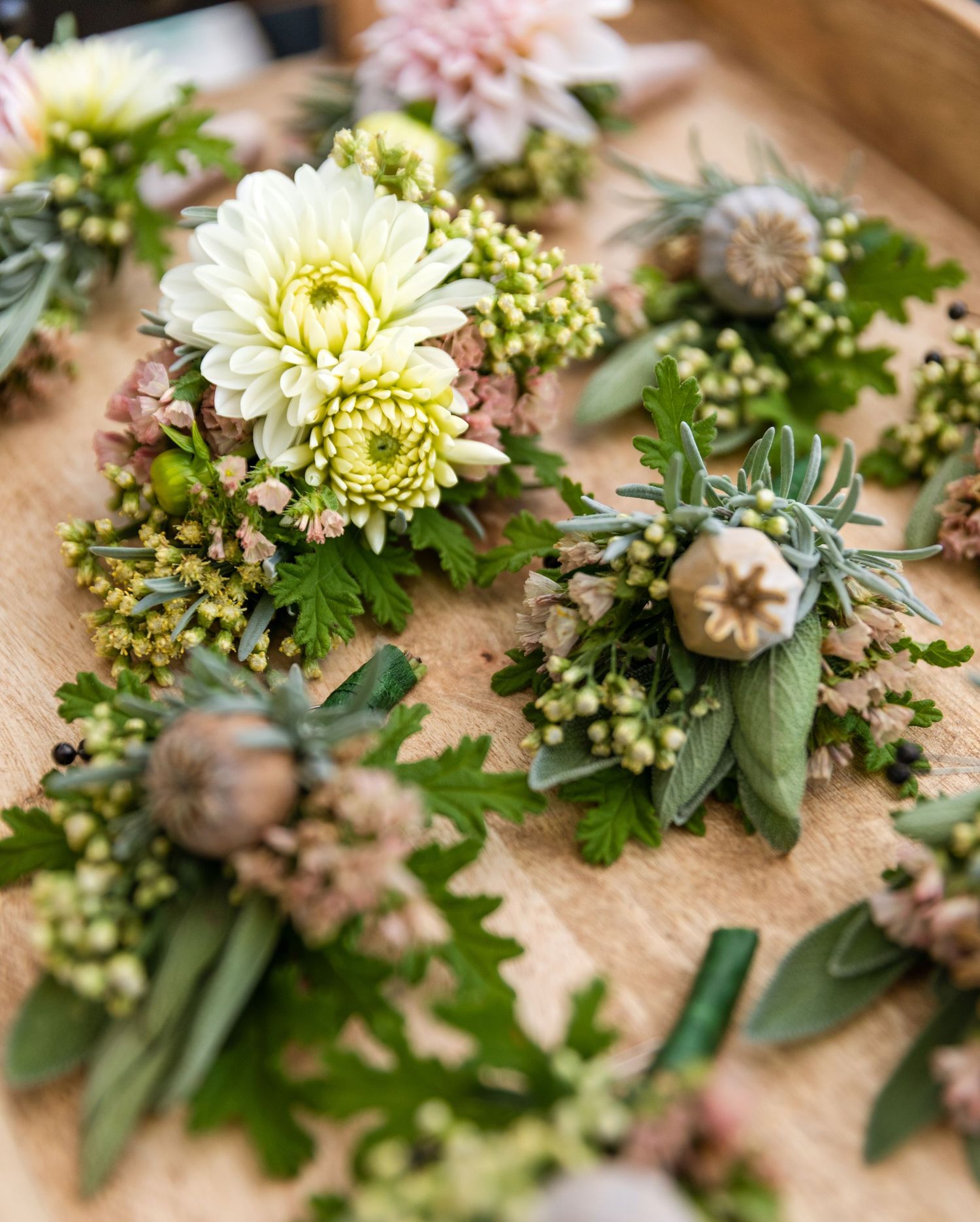 Close-up of delicate pink and white floral wedding bouquet arrangements laid out on a natural beige surface.