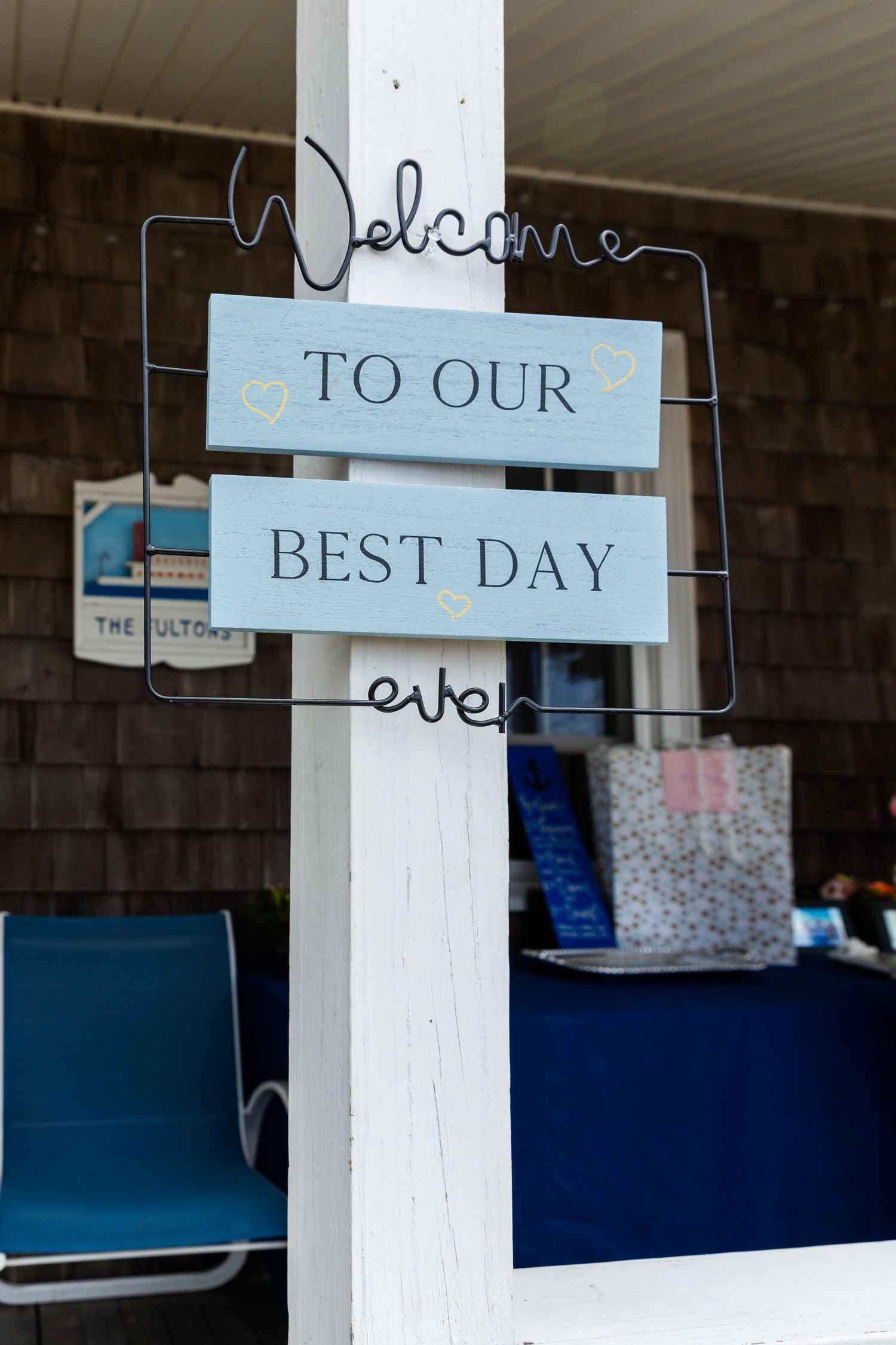 A decorative welcome sign reading 'To Our Best Day Ever' mounted on a white post with blue and black furnishings visible.