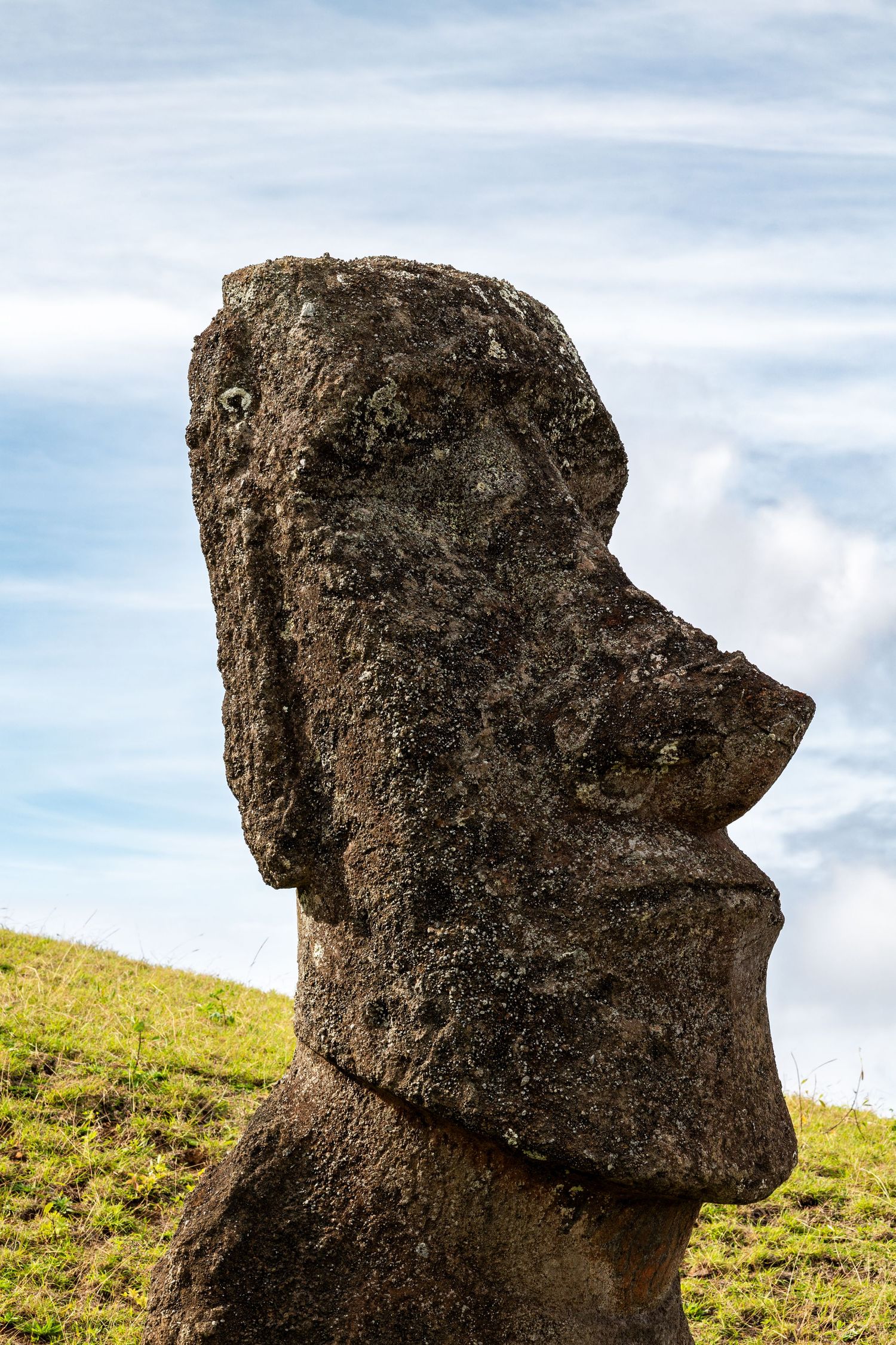 Close up view of ancient moai statue head profiles on Easter Island showing weathered volcanic rock details against blue sky.