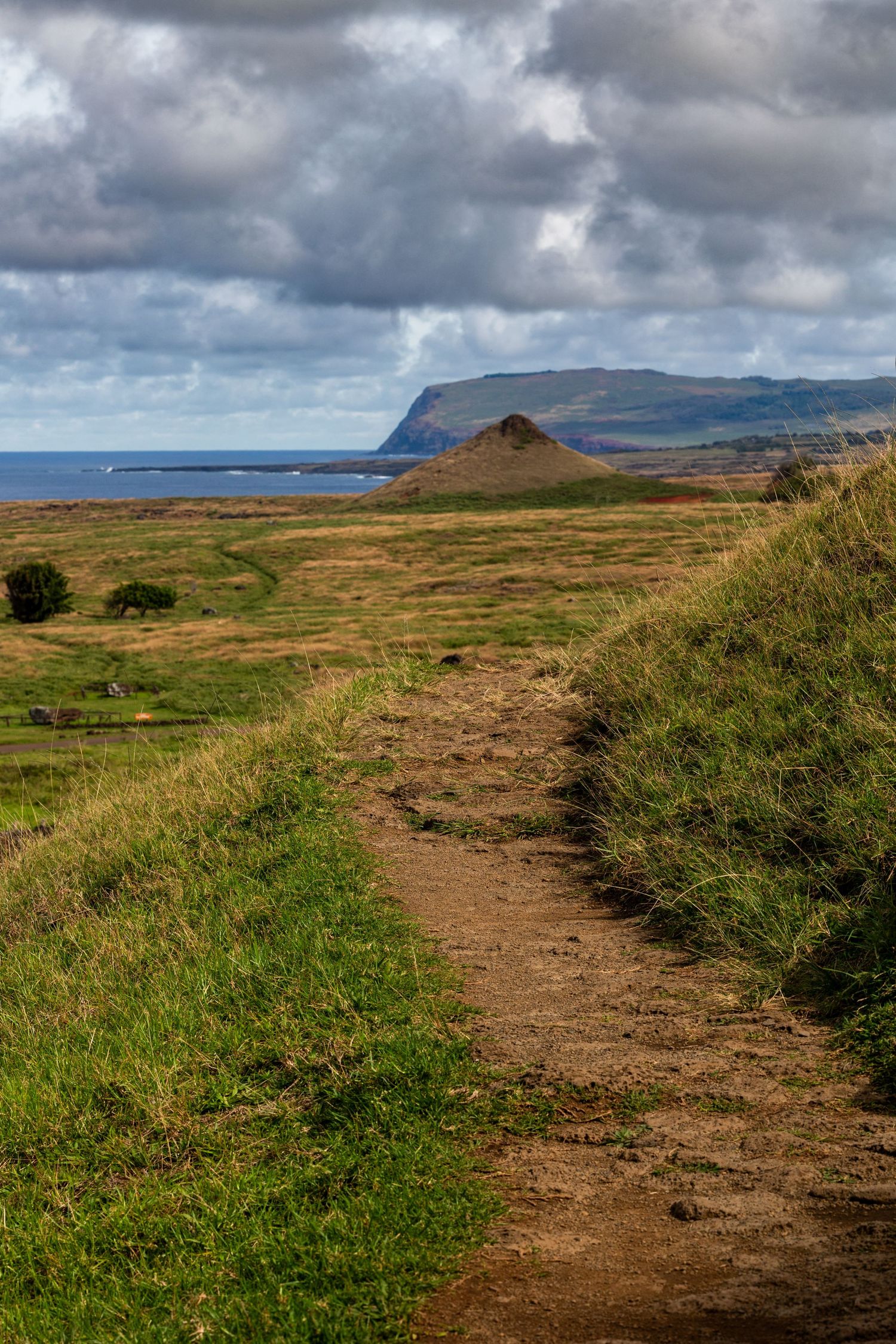 A dirt hiking trail winds along the rugged coastline of Northern Ireland with dramatic cliffs and moody clouds overhead.