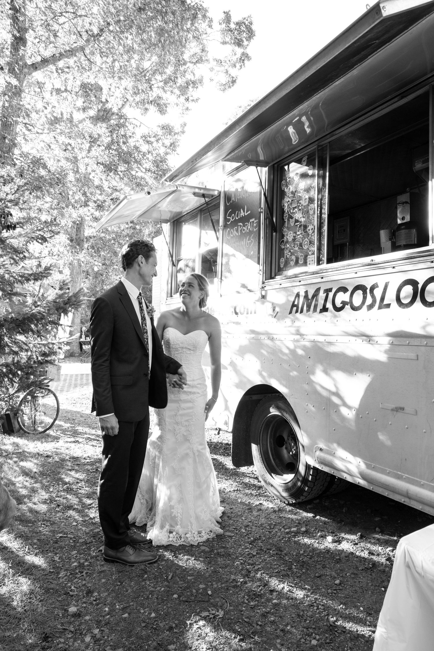 A couple poses near a vintage Airstream trailer on their wedding day in black and white photography.