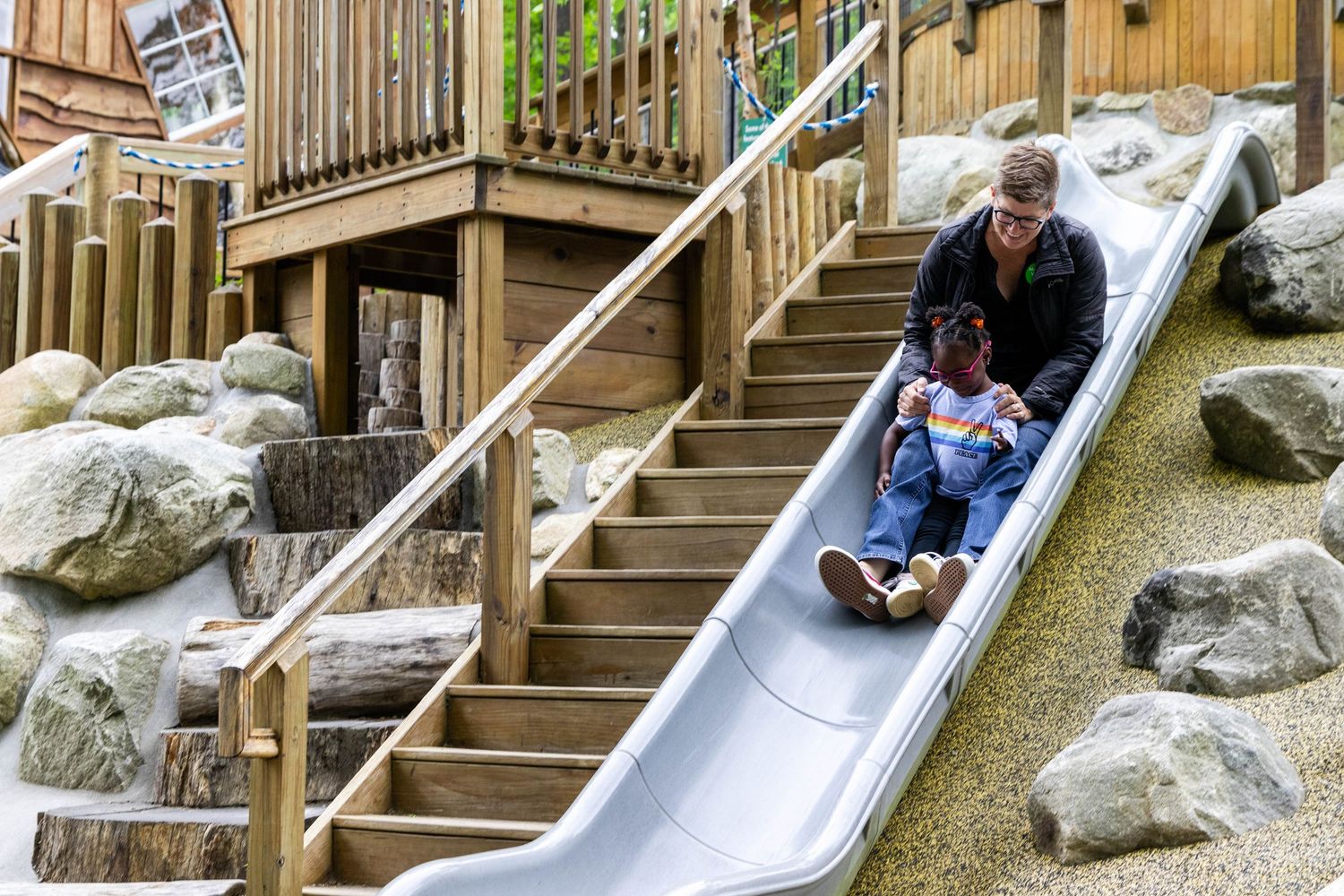 Sequence of photos showing a child sliding down a metal slide alongside a wooden deck and rock landscaping.
