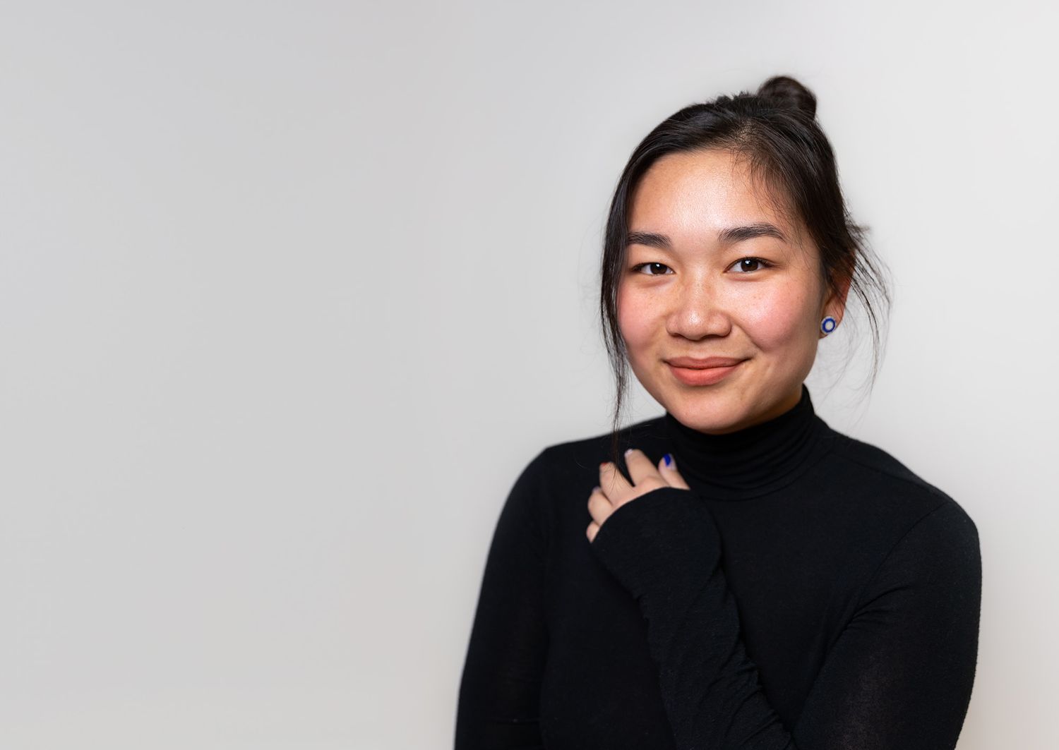 A person in black turtleneck sweater poses against white background.