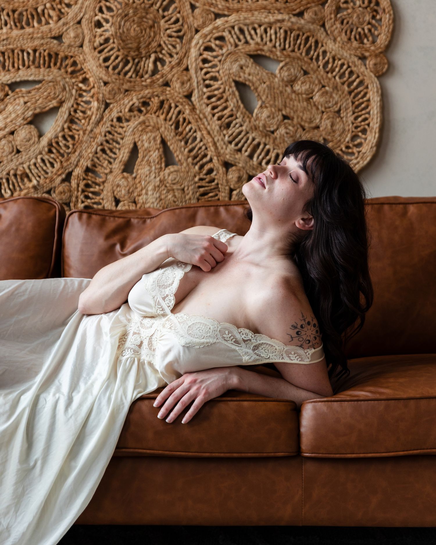 Artistic portrait on brown leather couch with vintage lace dress.