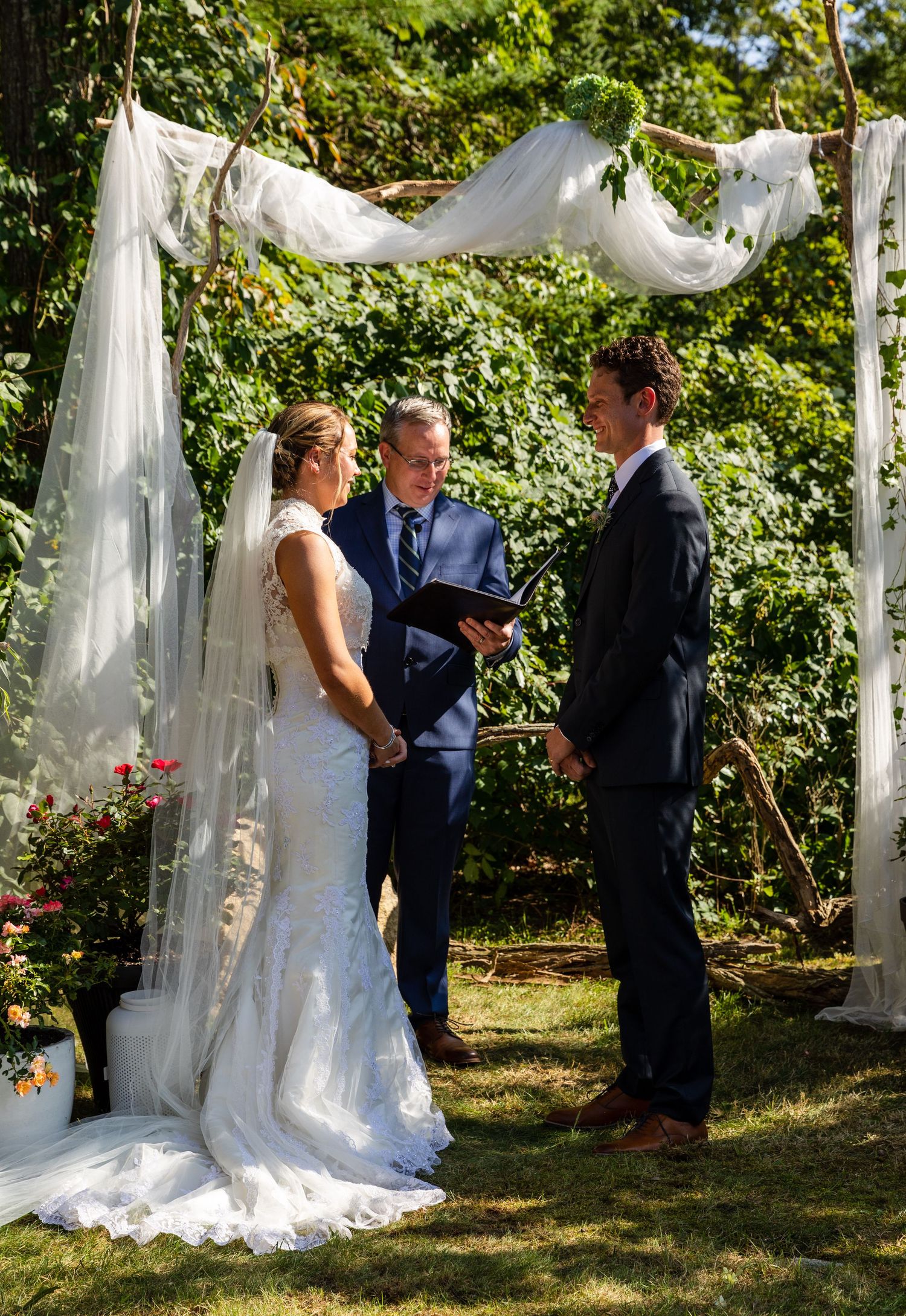 Outdoor garden ceremony scene with elegant white decor and flowing curtains creating an intimate atmosphere.