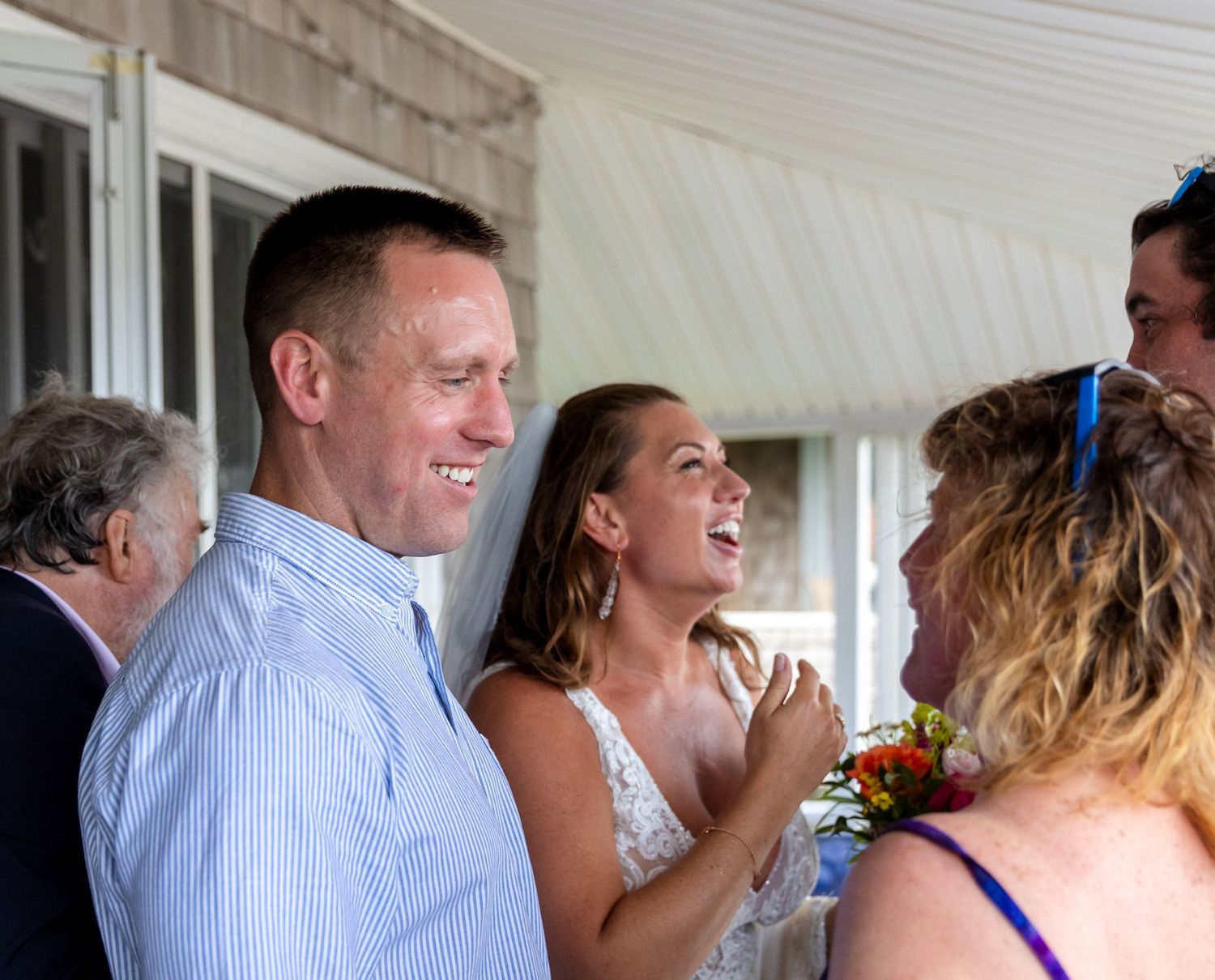 A candid moment of laughter and joy shared between guests at a covered outdoor gathering.