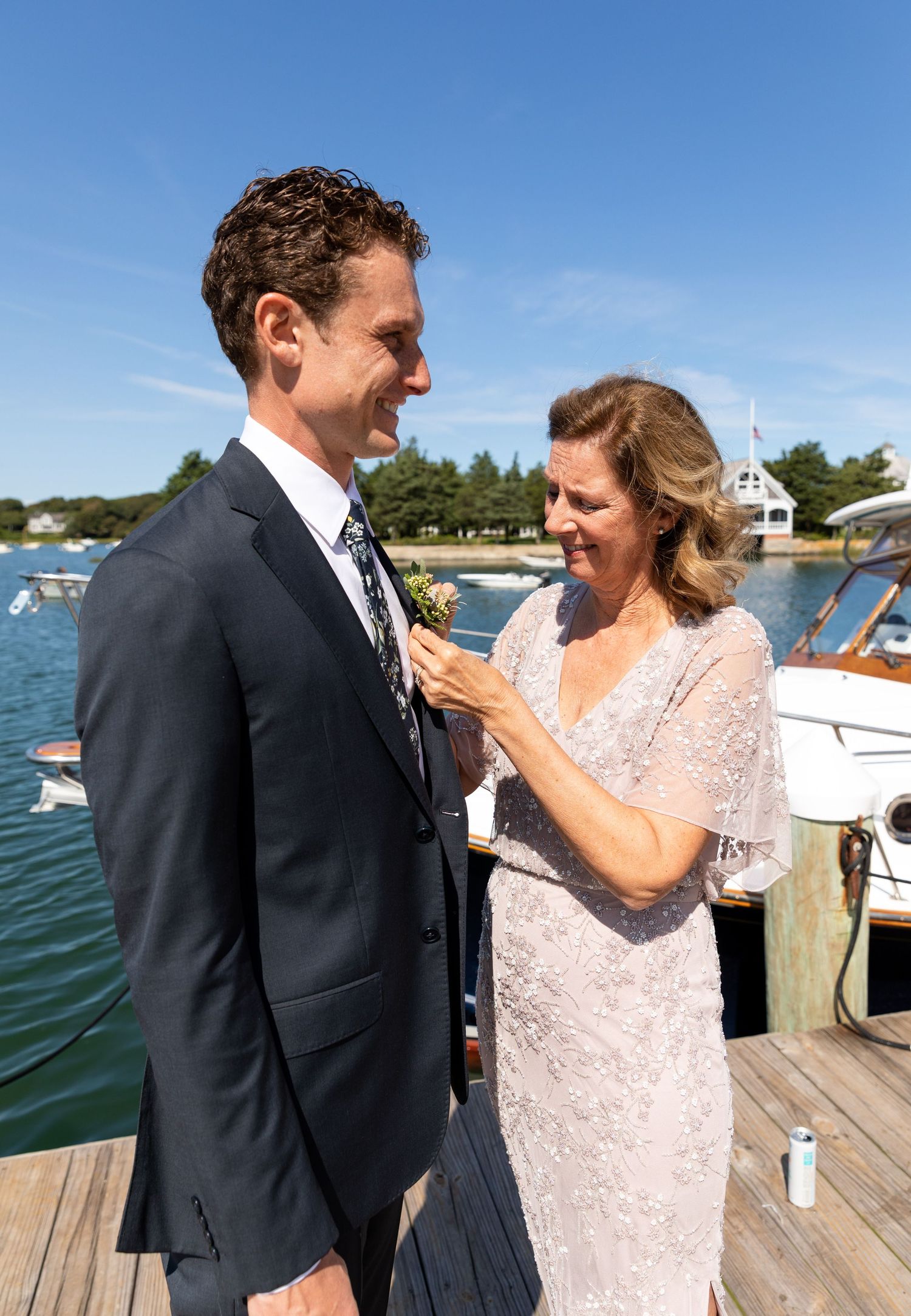 Two people share a happy moment on a sunny wooden dock by the water.