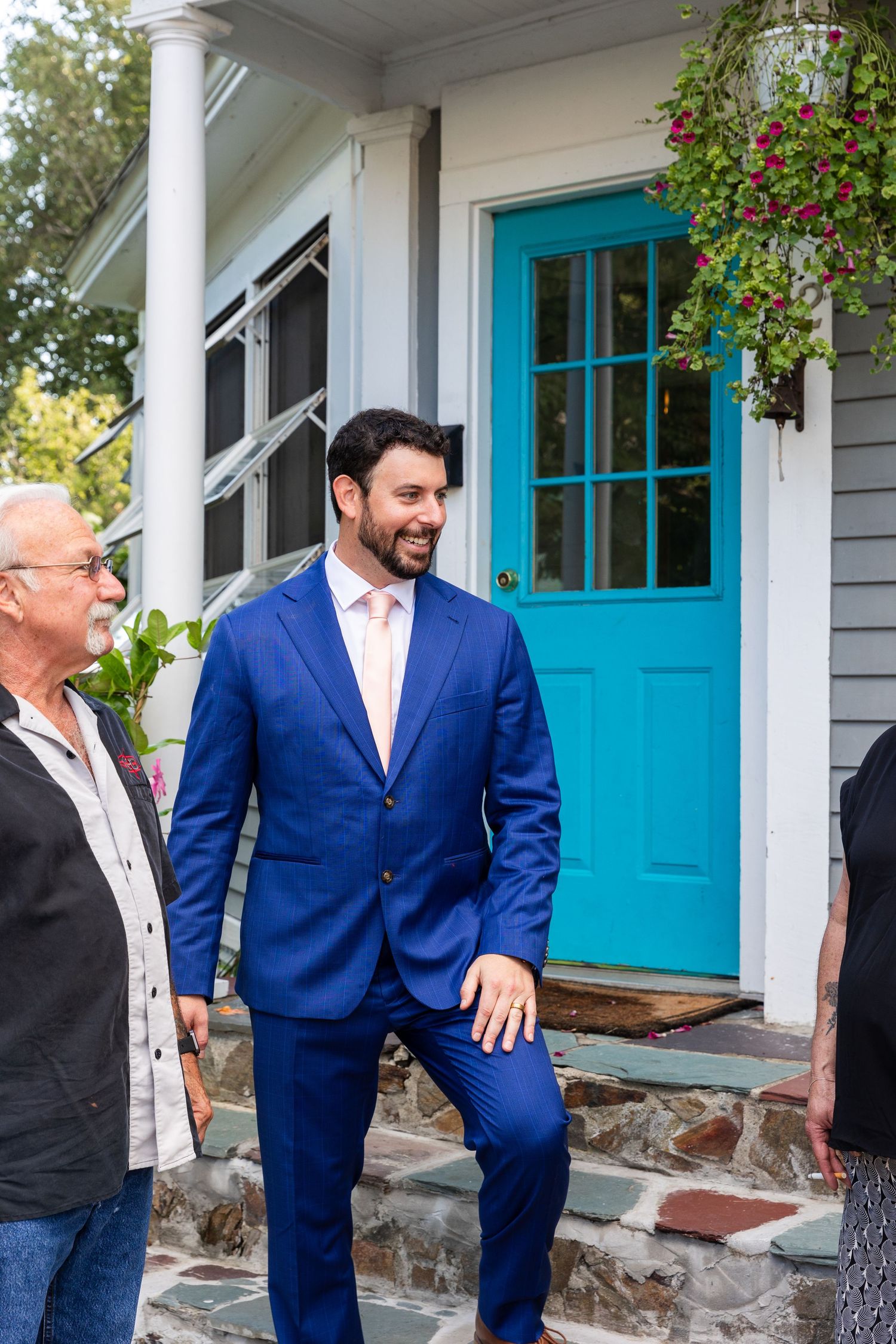 Outdoor scene shows people smiling and laughing together near a house with a bright turquoise blue front door.