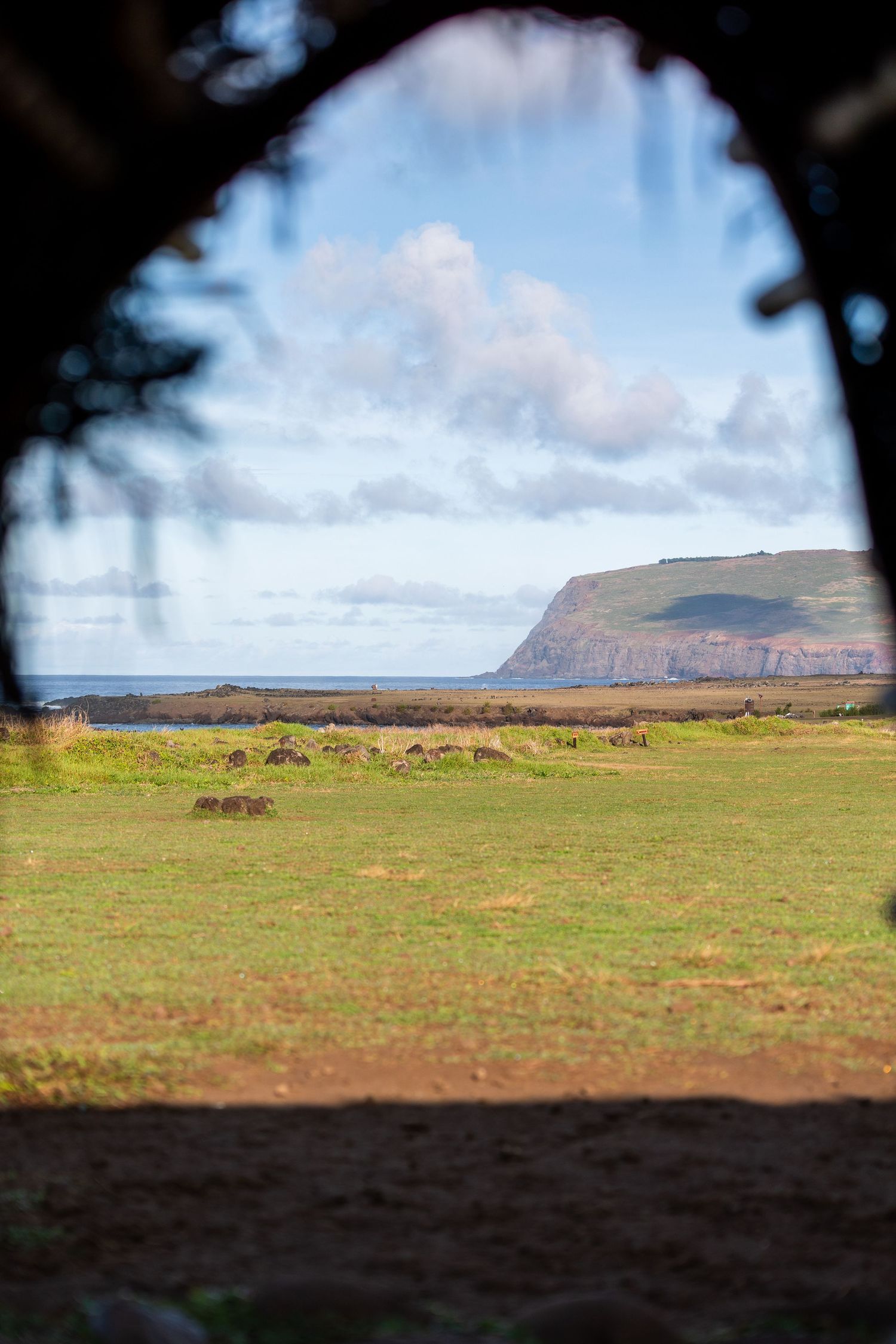 Panoramic landscape view of Easter Island's grassy plains with rolling hills and mountains under cloudy skies.