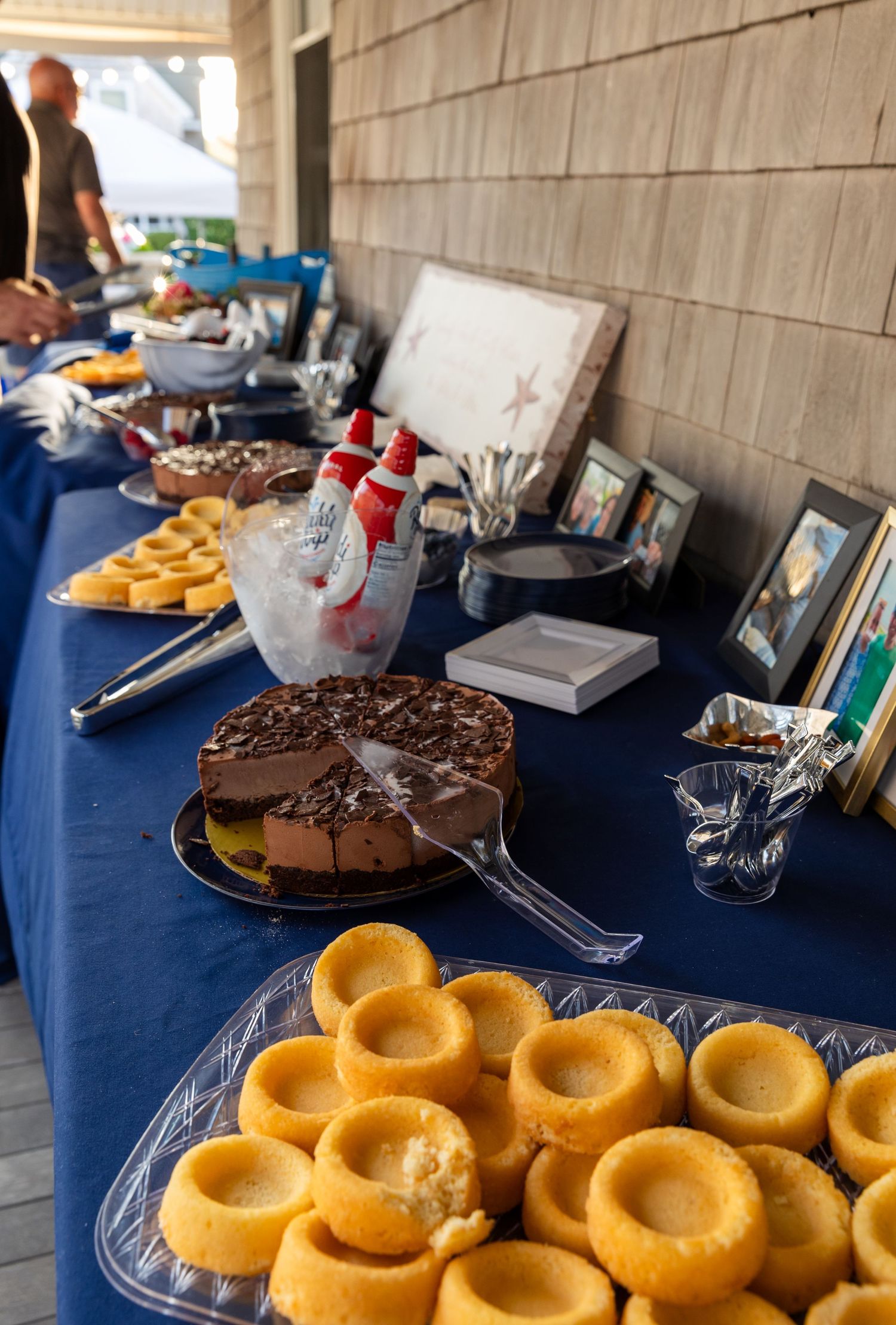 Golden donuts and chocolate cake arranged on a navy blue tablecloth at a dessert buffet display.