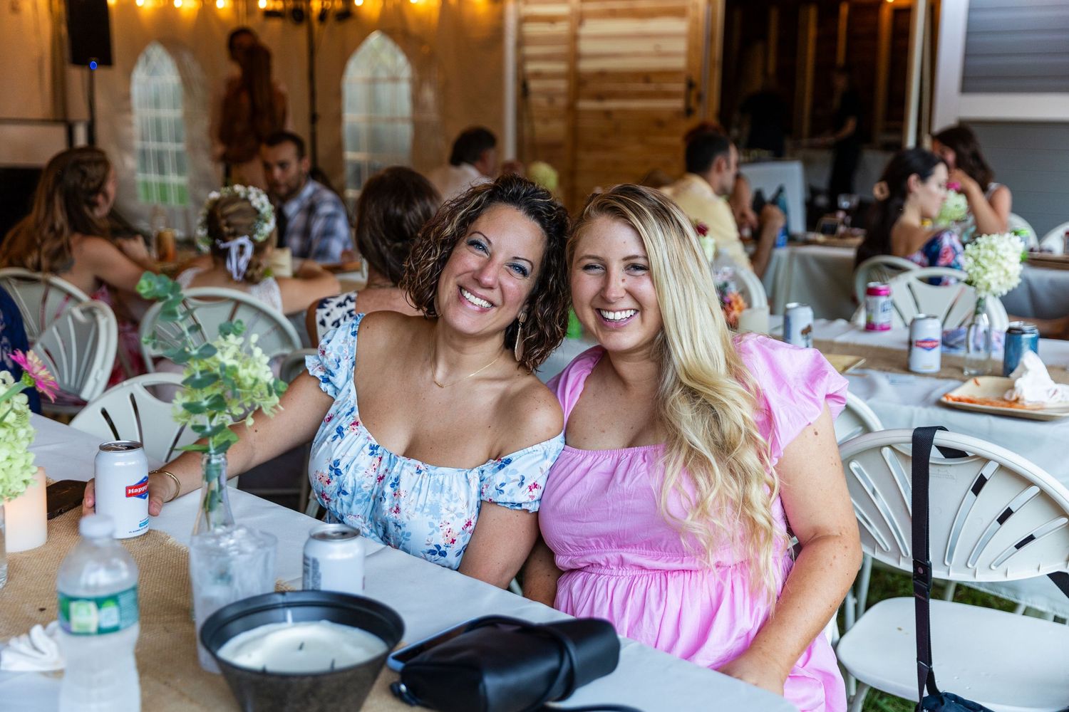 Elegant brunch celebration with floral centerpieces and pink decor in a rustic wood venue.