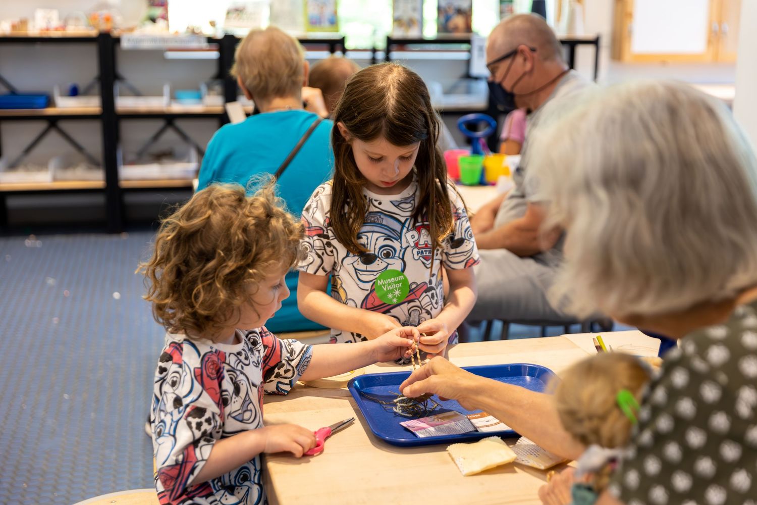 A sequence of images showing children and adults collaboratively working on projects and activities at tables in a classroom setting.