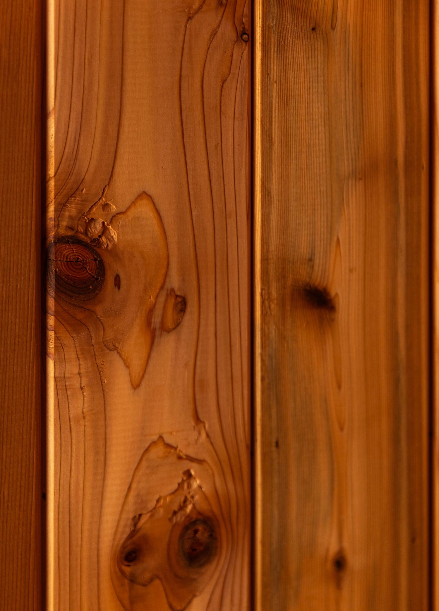 Close-up of natural wood planks with knots and grain patterns showing rustic texture in warm brown tones.