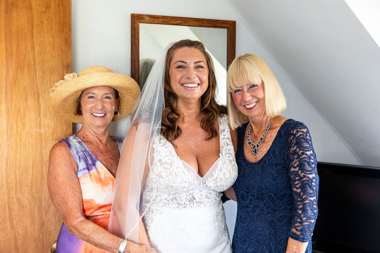 A group of joyful wedding party members in light and navy blue dresses share laughter while getting ready.