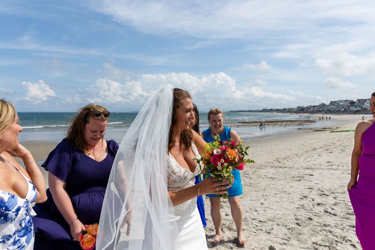 Beautiful beach wedding ceremony taking place on a sunny day with bright blue skies and ocean waves in the background.