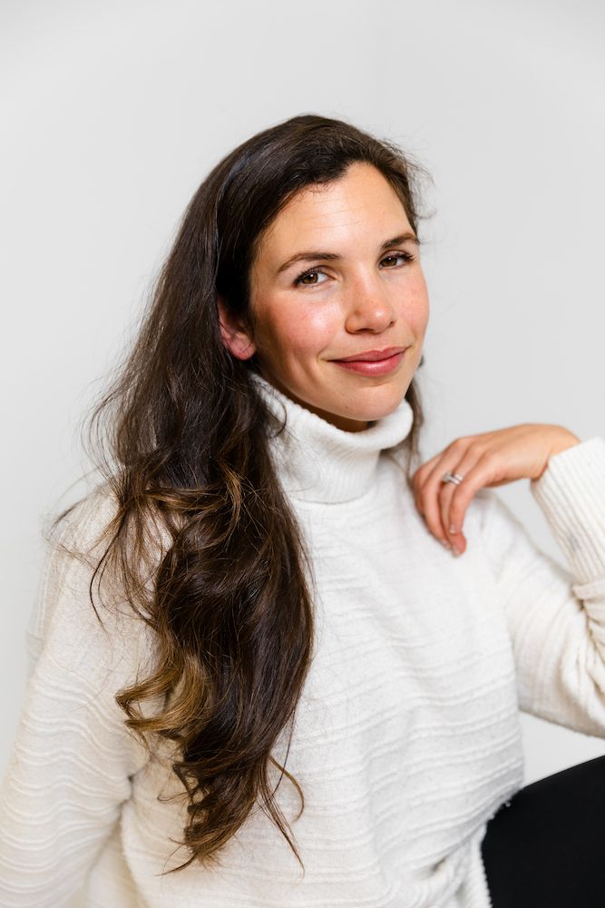 Portrait featuring a white turtleneck sweater against a neutral gray background.