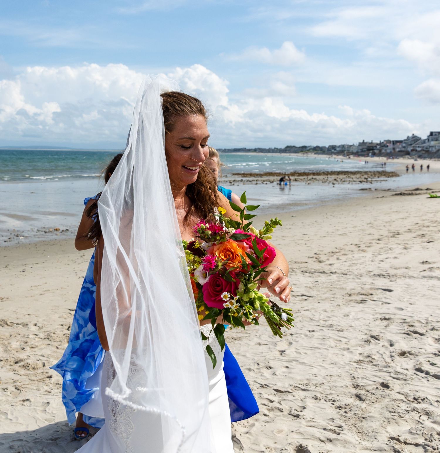 A beautiful wedding ceremony takes place on a sunny beach with white sand and blue ocean views.