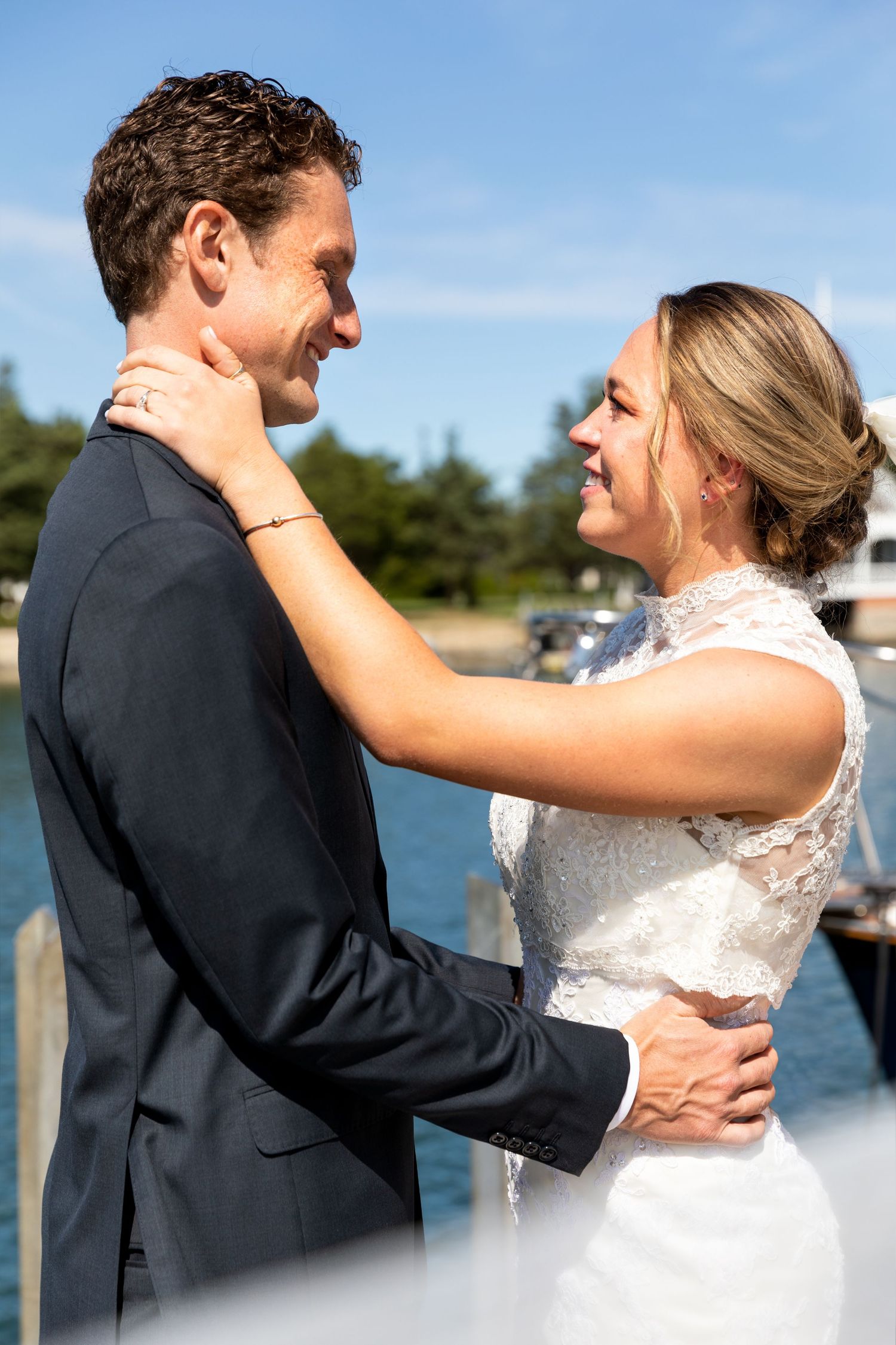 A tender wedding moment between a couple sharing an embrace by the waterfront on their special day.