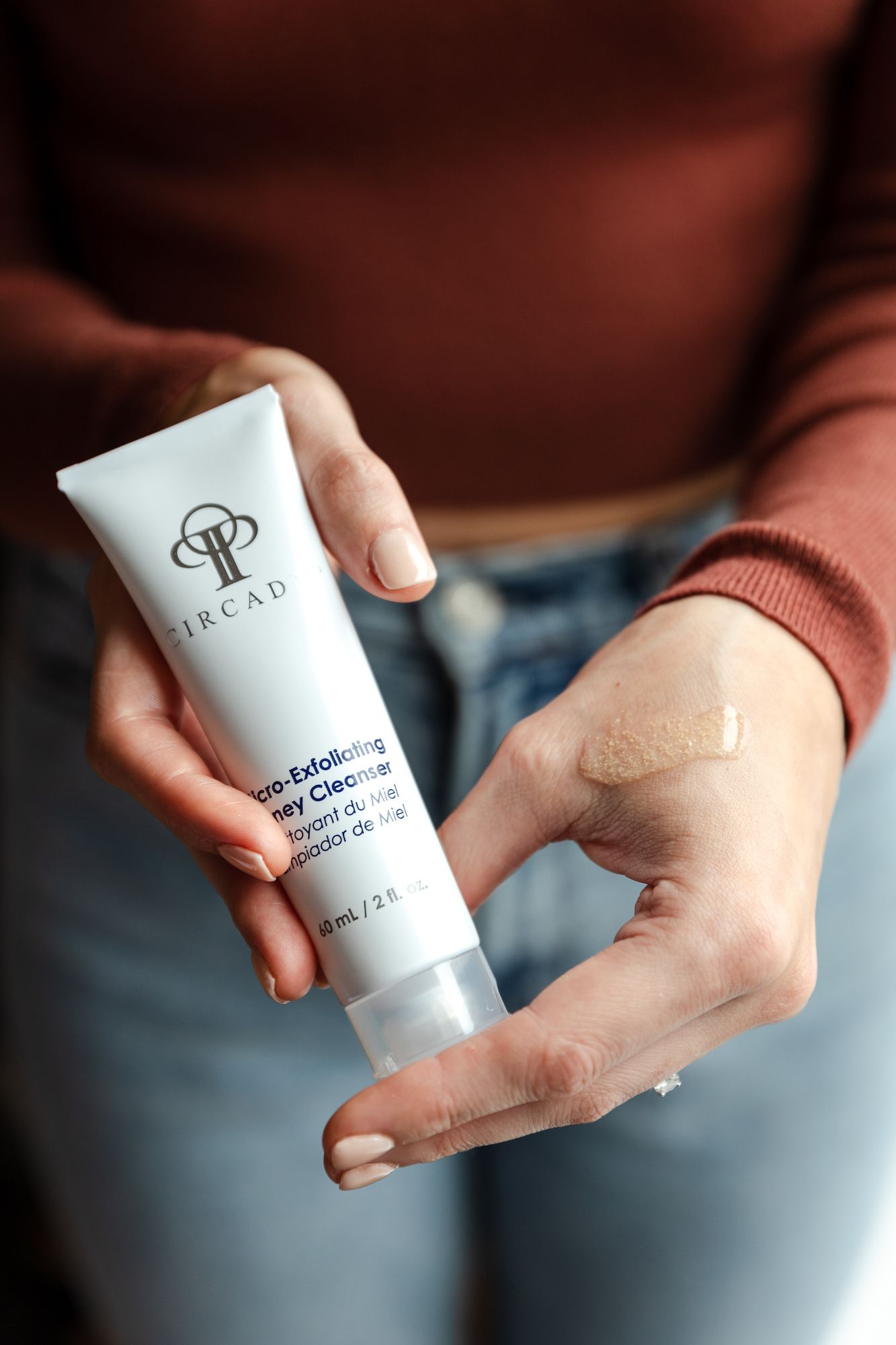 Hands demonstrating skincare product application with TRCAD cream tube.