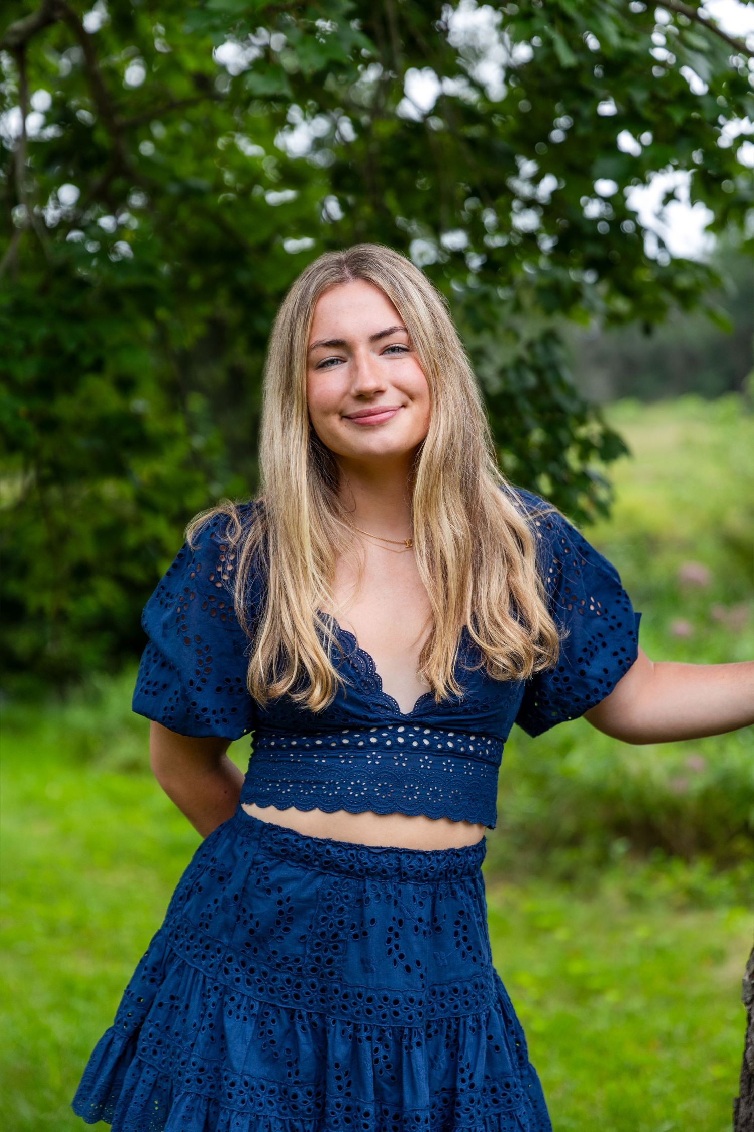Outdoor portrait of someone in navy blue two-piece lace outfit against green garden background.